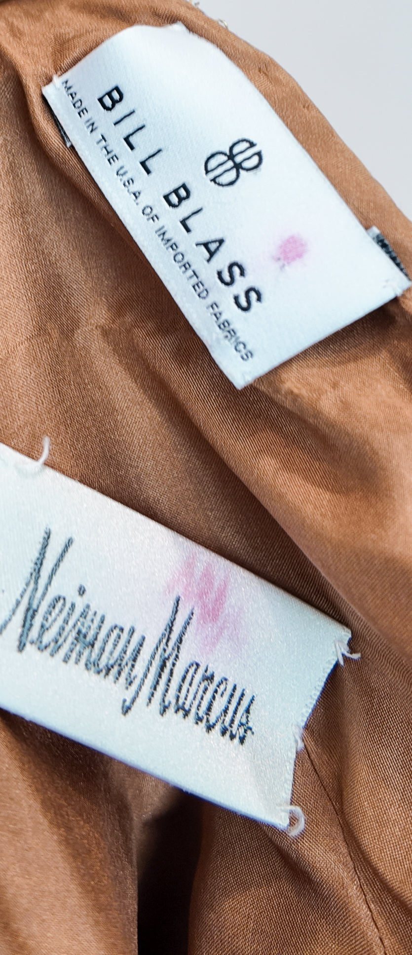 Close-up of Bill Blass and Neiman Marcus labels on a brown fabric background