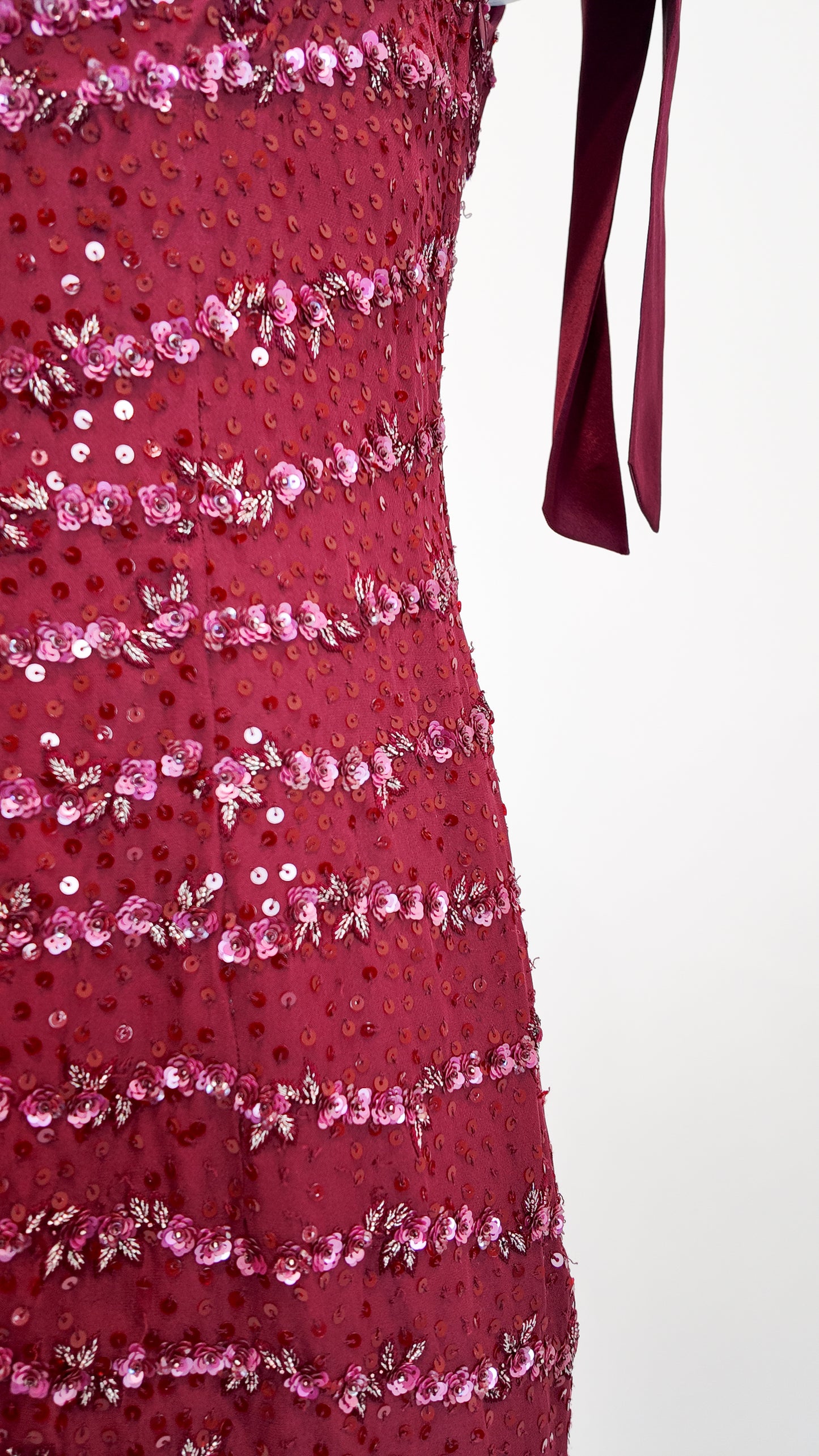Close-up of a red dress with pink sequin details on a white background
