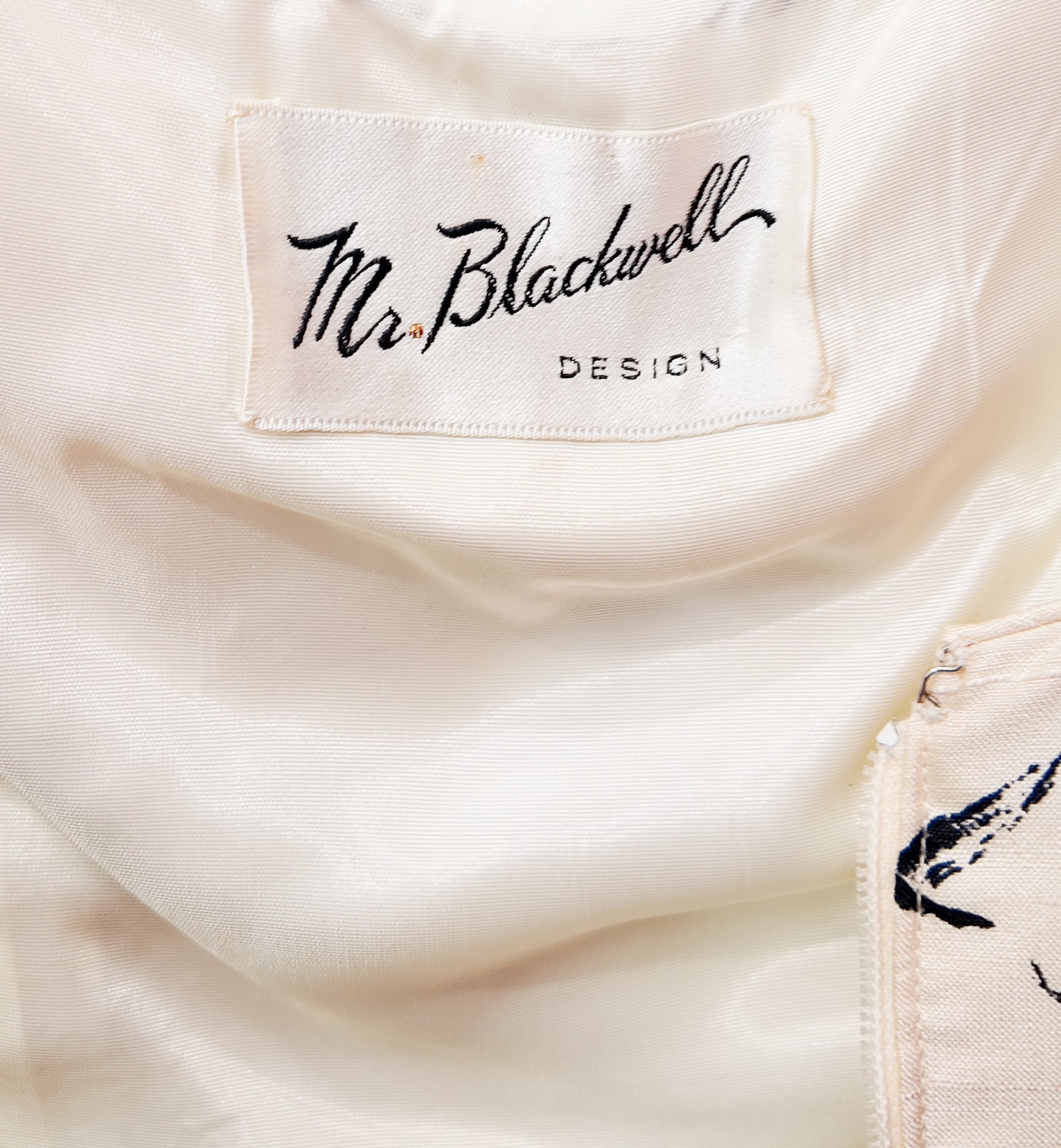 Close-up of a white garment with 'Mr Blackwell Design' label