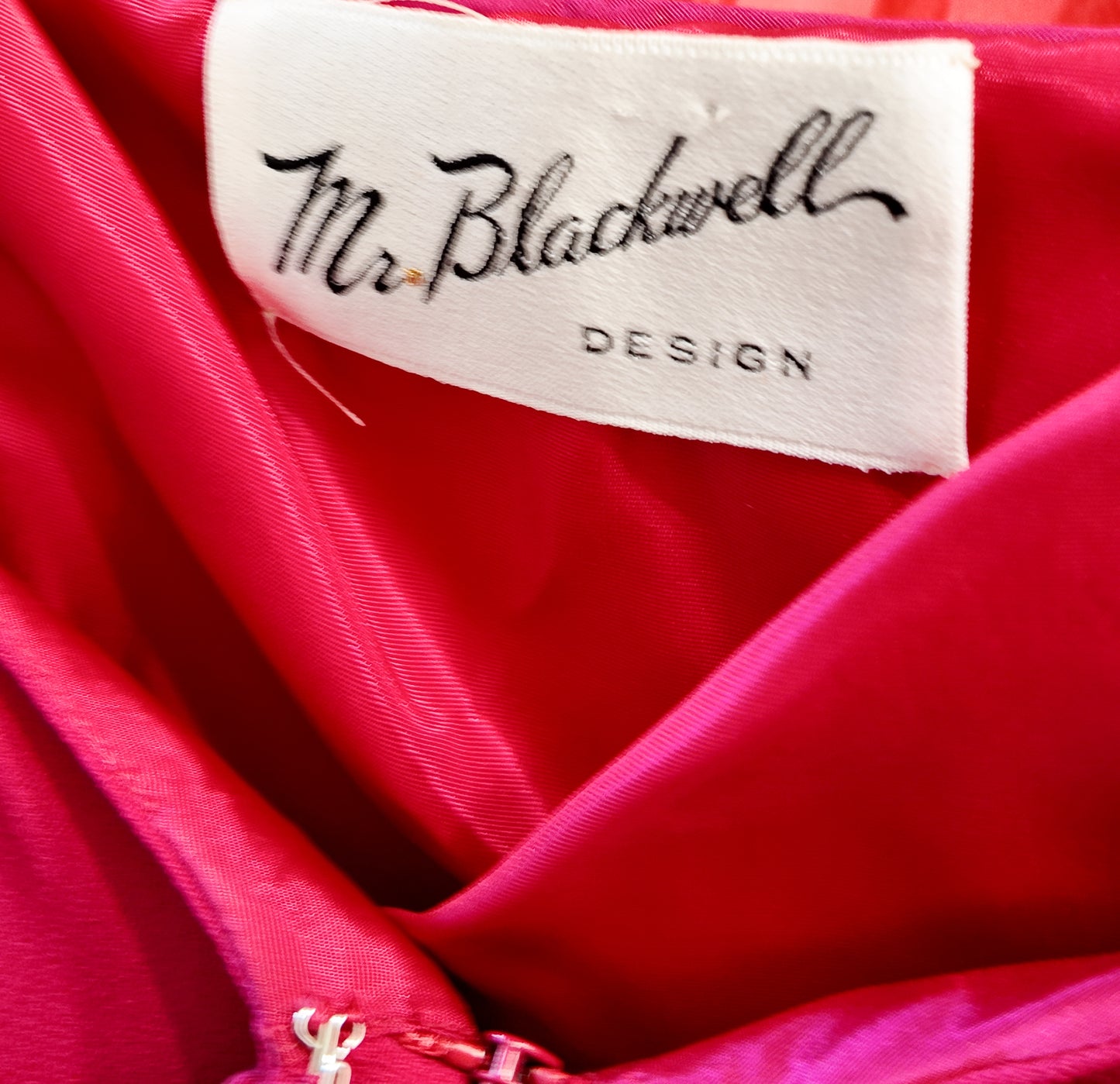 Close-up of a pink fabric with 'Mr. Blackwell Design' label.