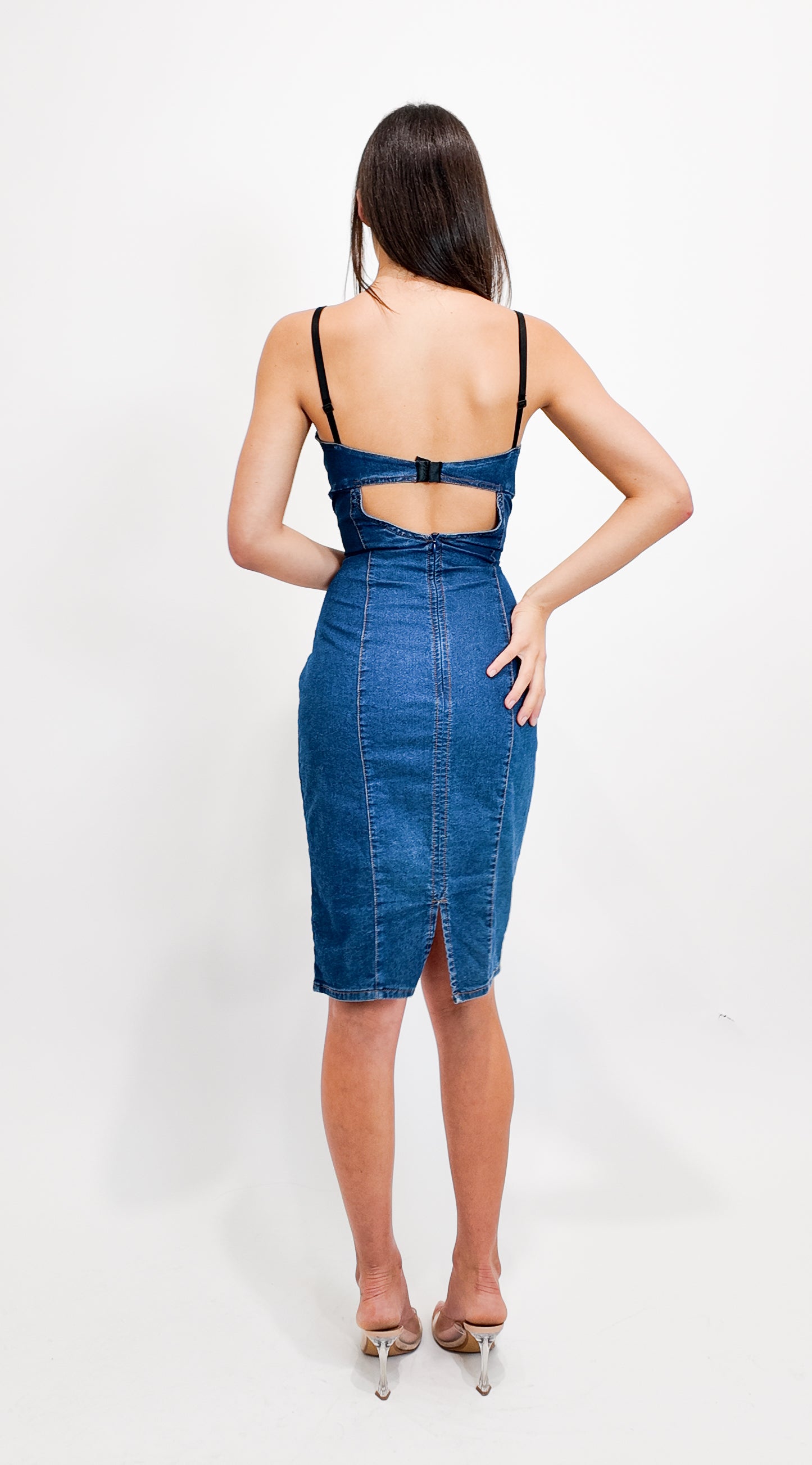 Woman wearing a blue denim dress with cut-out design on a white background