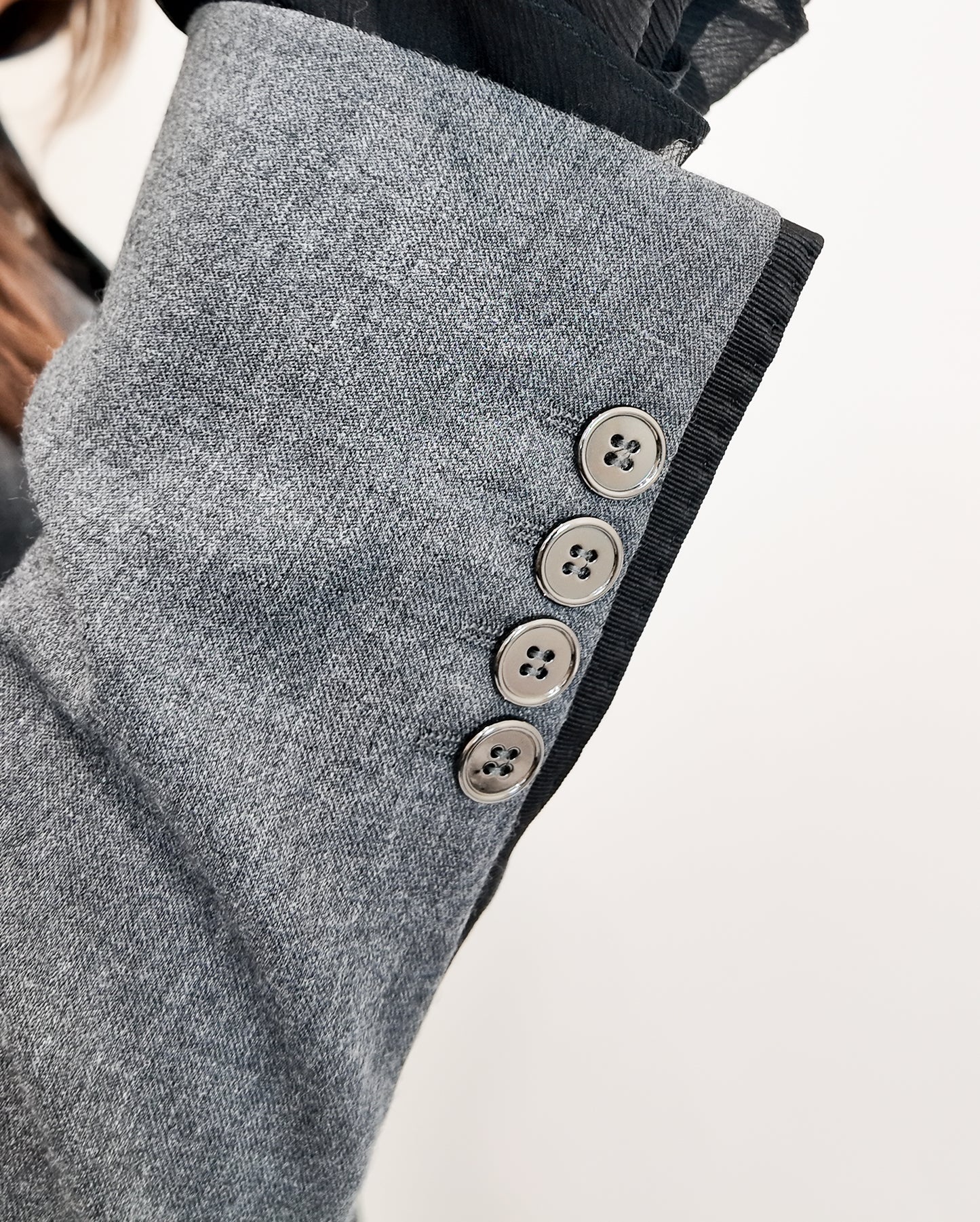 Close-up of a gray coat with button details on a light background
