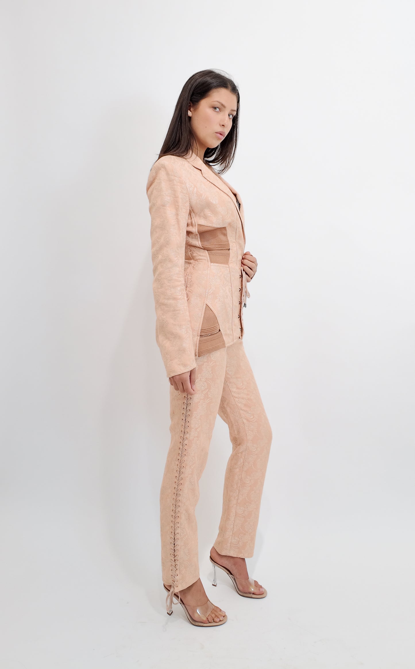 Woman wearing a nude corseted Jean Paul Gaultier suit on a white background