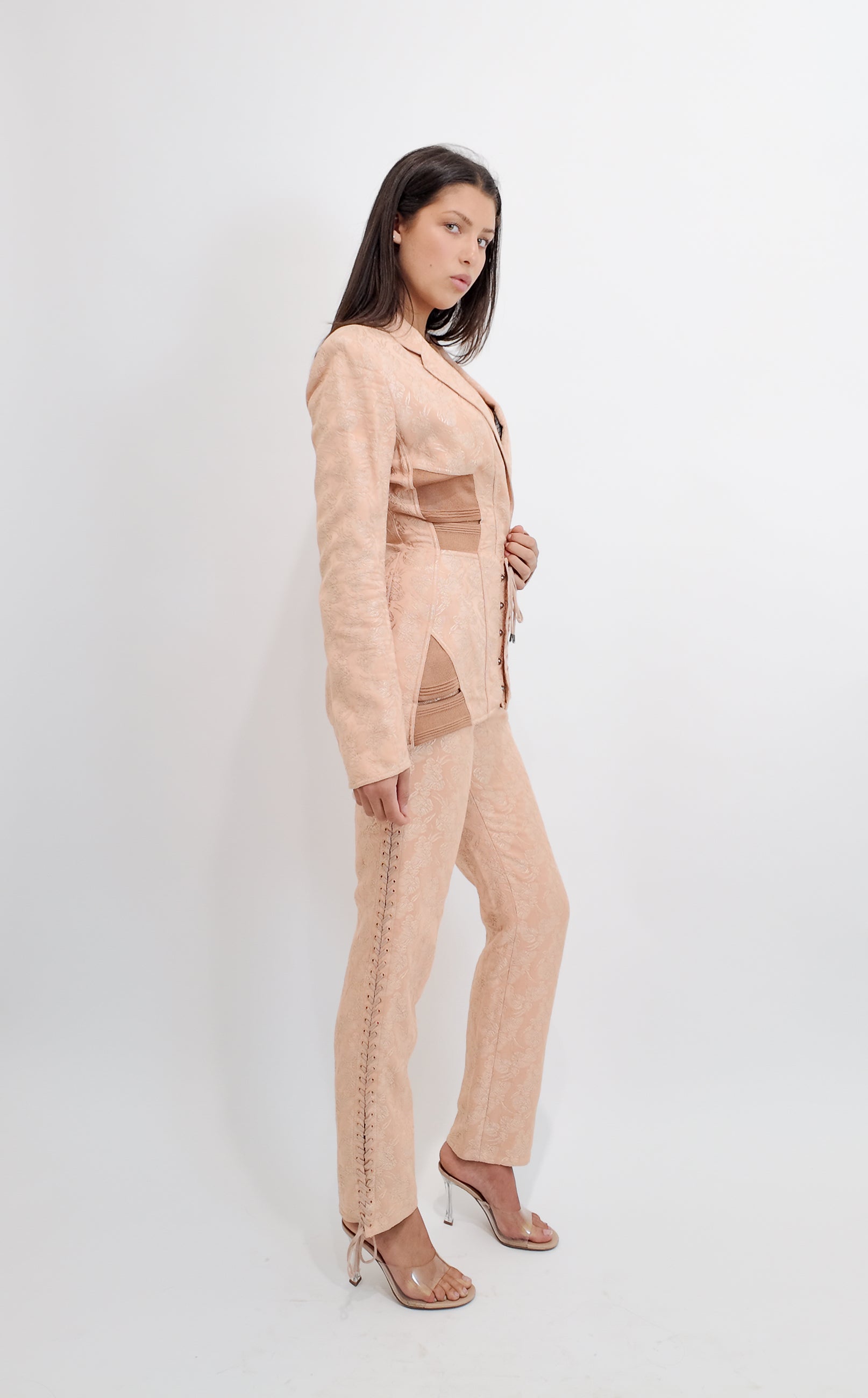 Woman wearing a nude corseted Jean Paul Gaultier suit on a white background