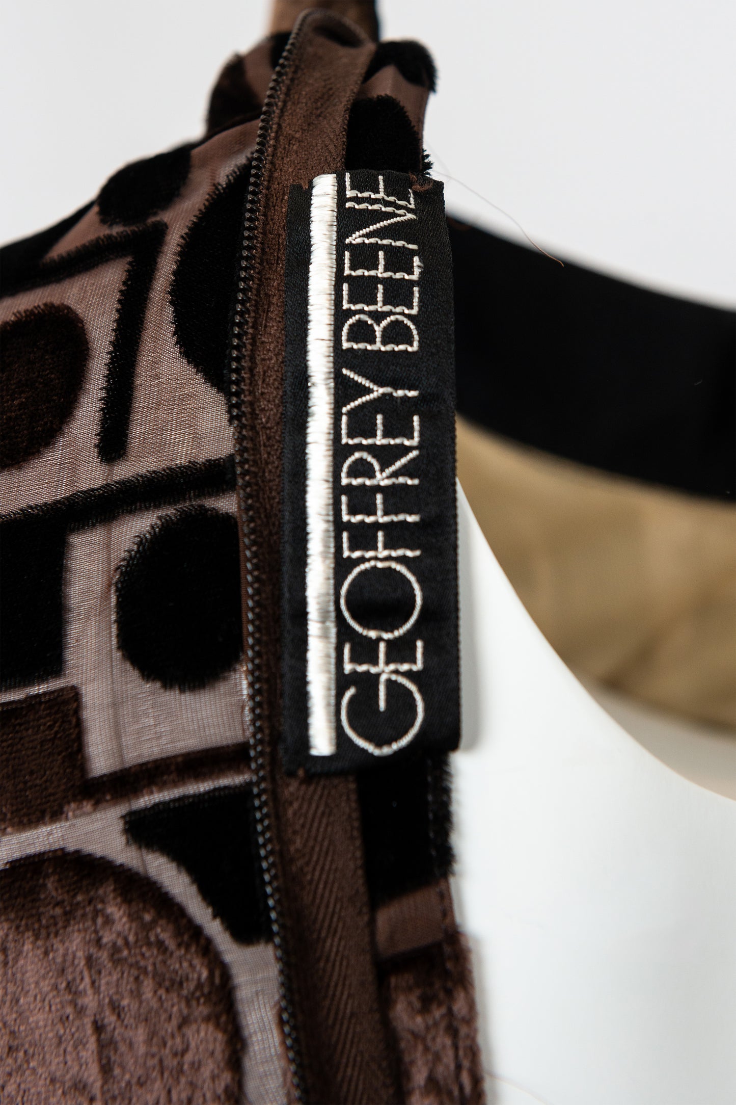 Close-up of a Geoffrey Beene label on a patterned garment with a white background.