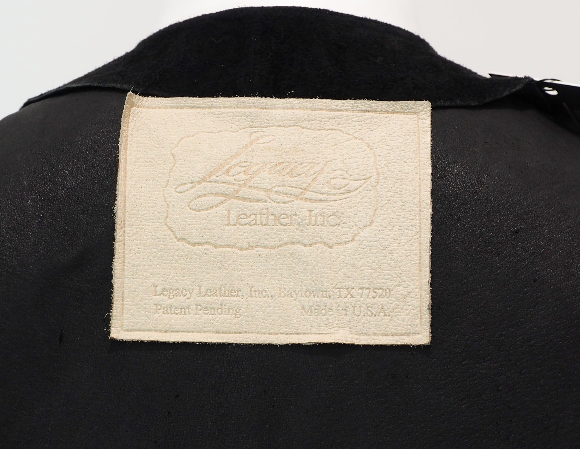 Close-up of a Legacy Leather Inc. label on a black leather product.