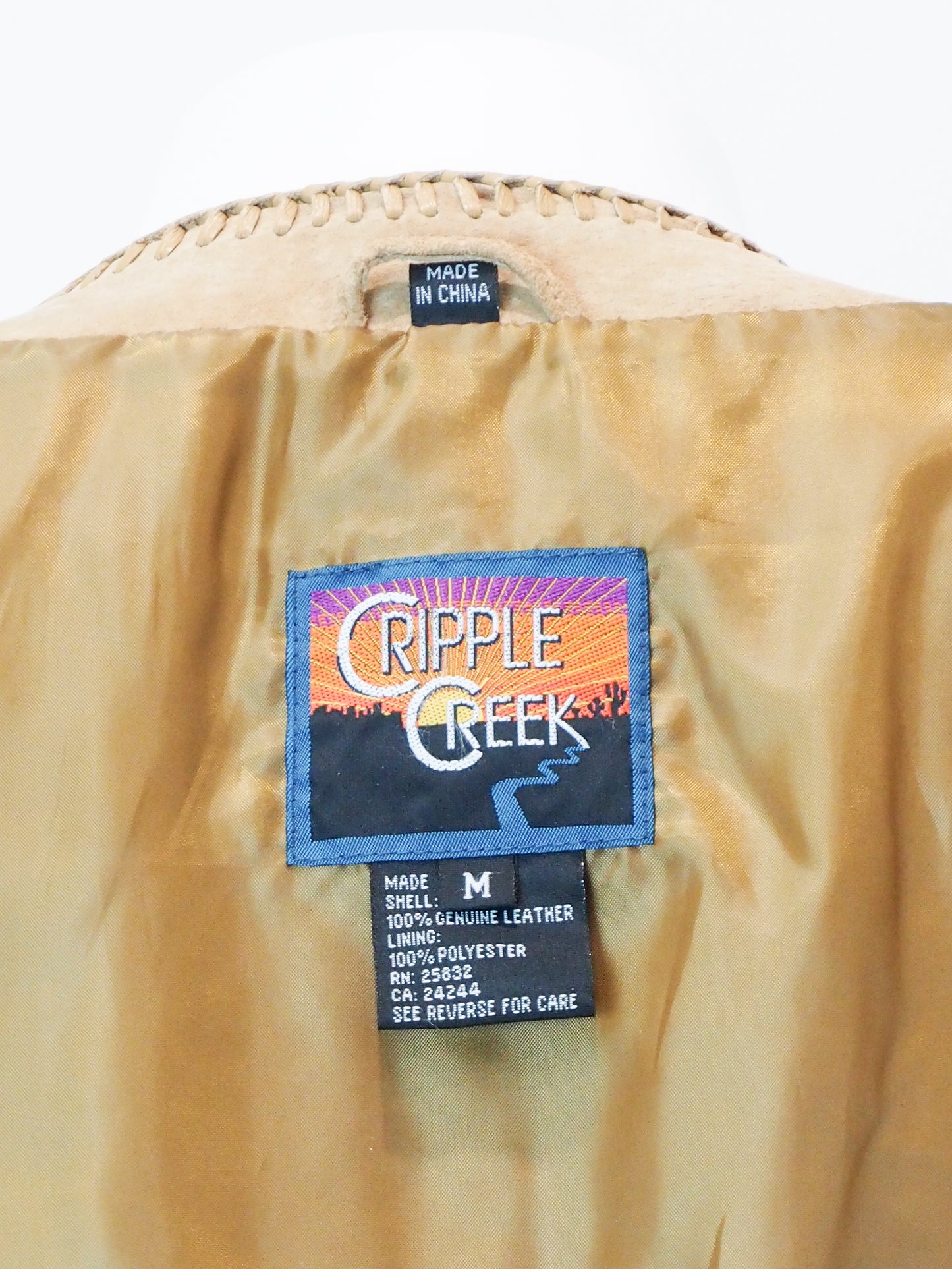 Cripple Creek label on a beige jacket with a white background