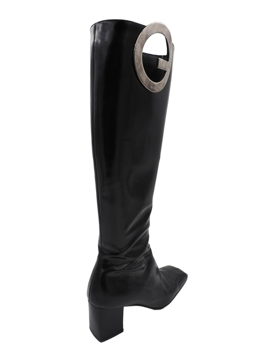 A vintage gucci 1990s black leather knee-high boot with a chunky block heel and a large circular silver-tone metal ring logo detail near the top shaft