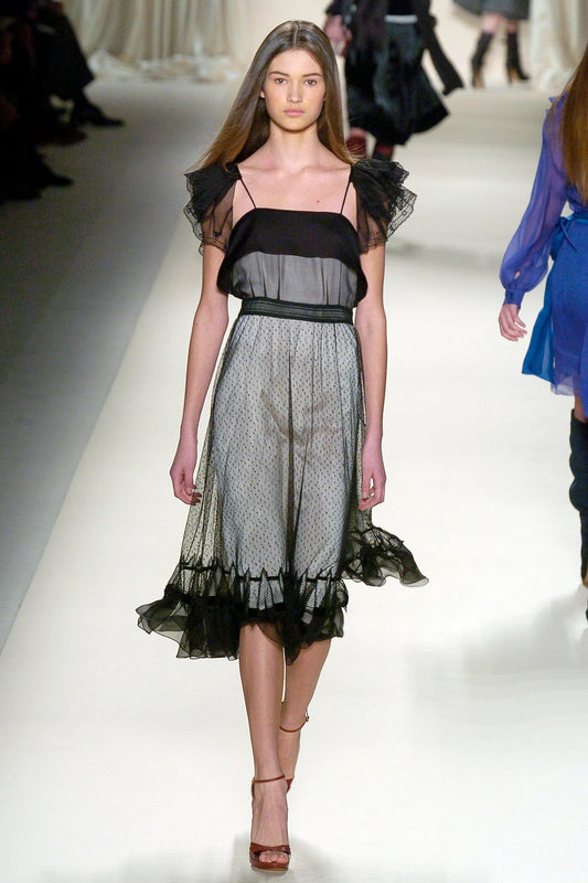 A vintage Chloe 2005 black sheer mesh dress with a solid black off-the-shoulder yoke, a polka-dotted tulle skirt, and ruffled trim details