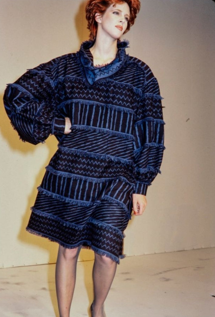 A vintage Issey Miyake long-sleeve, high-neck tunic top featuring a blue and black geometric pattern with fringed edges