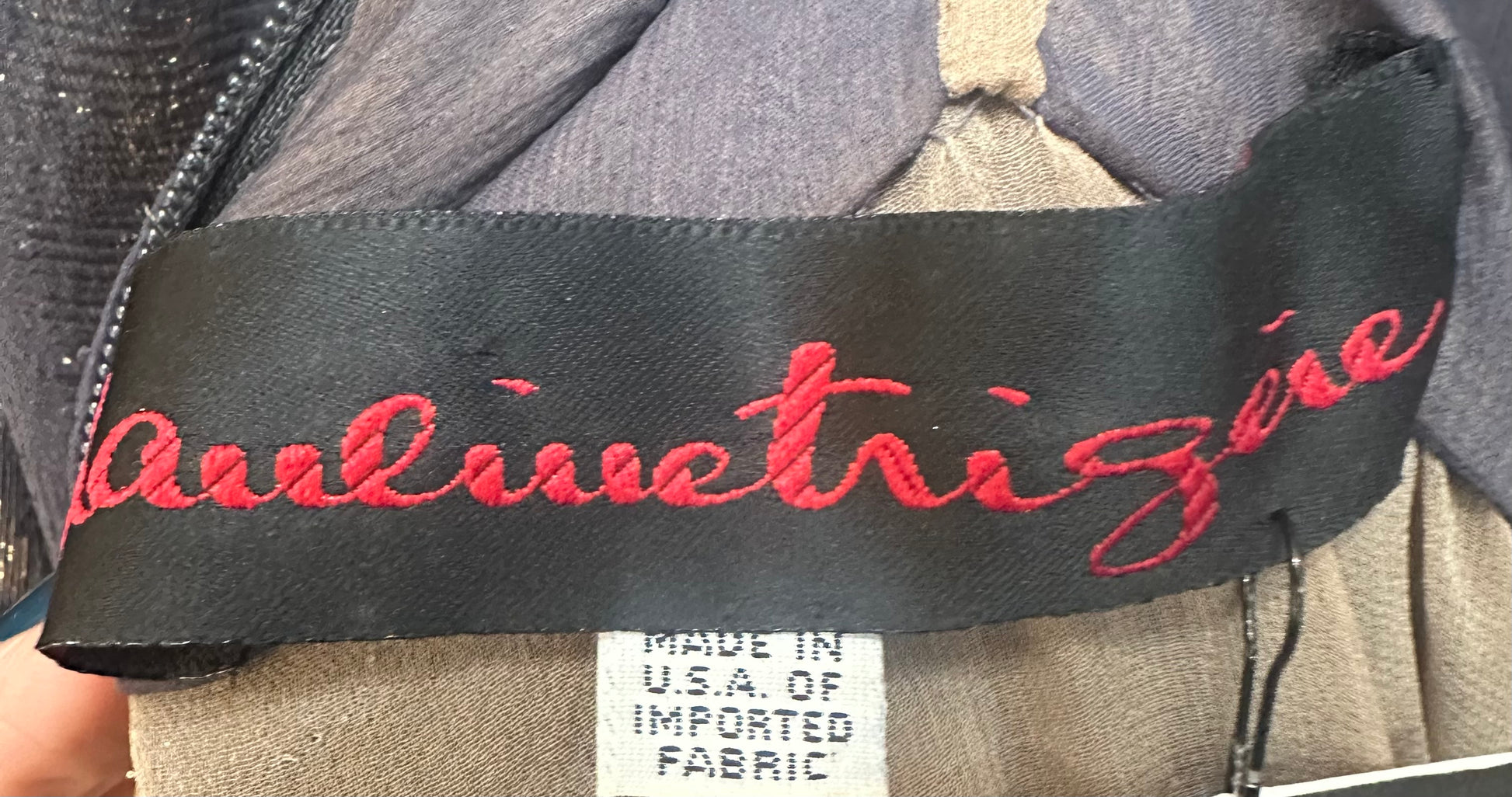 Close-up of a label with red text on a garment, featuring the brand name 'Pauline Trigere'.