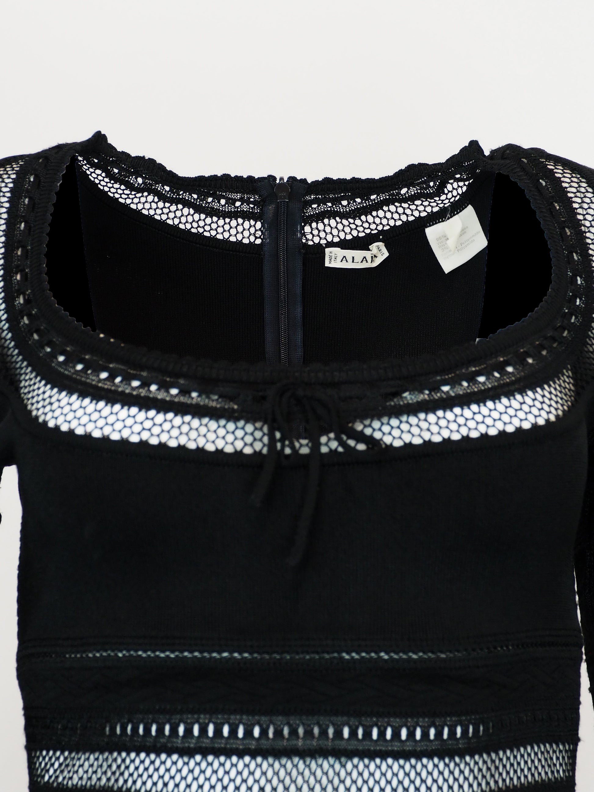 A vintage alaia 1993 black long-sleeve knit mini dress with horizontal openwork stripe patterns across the bodice, sleeves, and hem, featuring a scoop neckline with a front tie detail.