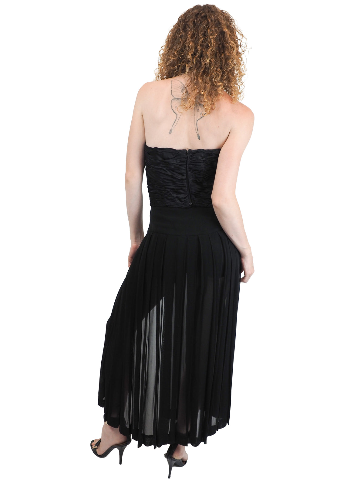 A vintage moschino black strapless high-low dress with a textured corset-style bodice, front cutout, and flowing sheer overlay skirt, paired with black heeled sandals