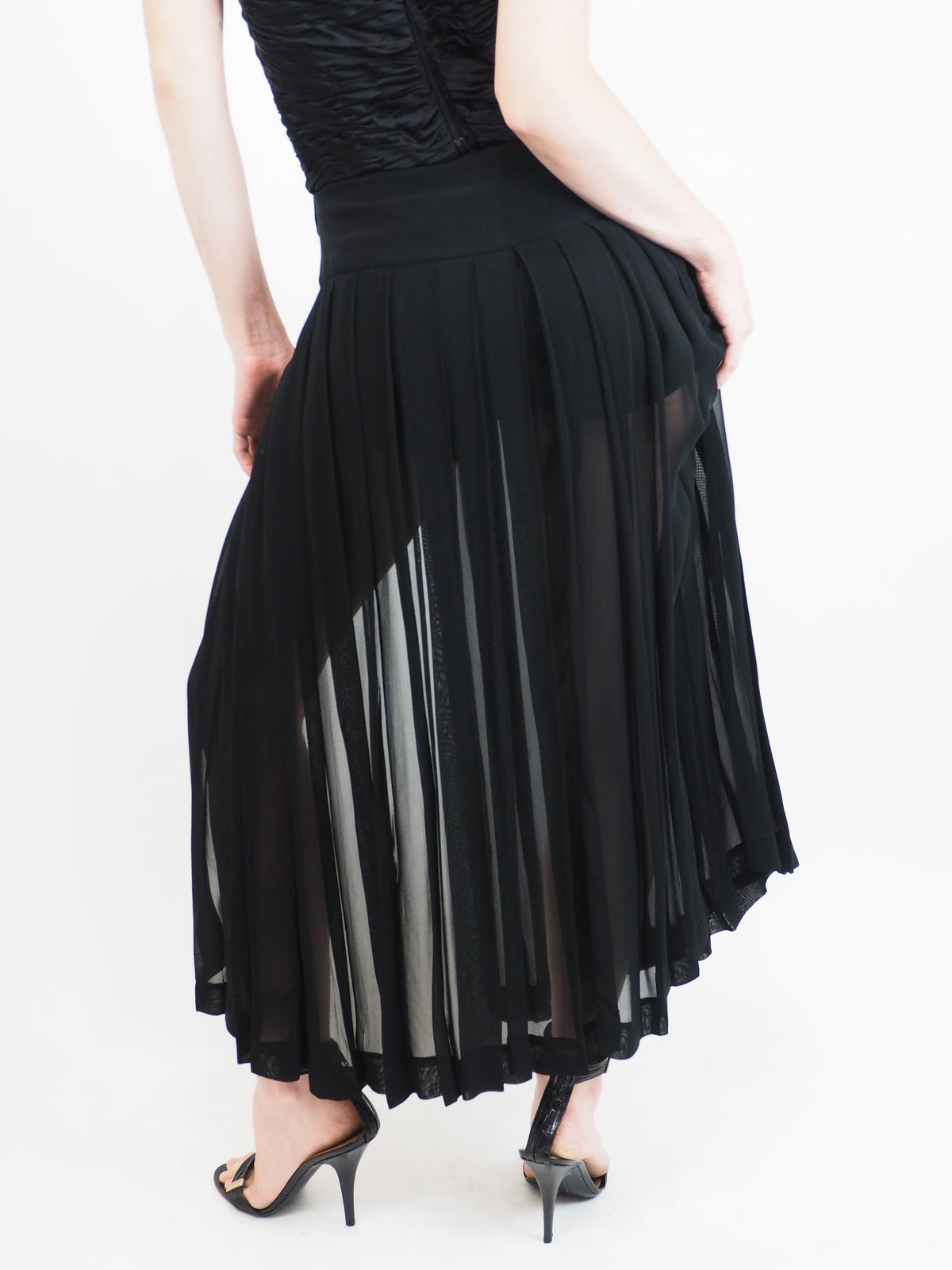 A vintage moschino black strapless high-low dress with a textured corset-style bodice, front cutout, and flowing sheer overlay skirt, paired with black heeled sandals
