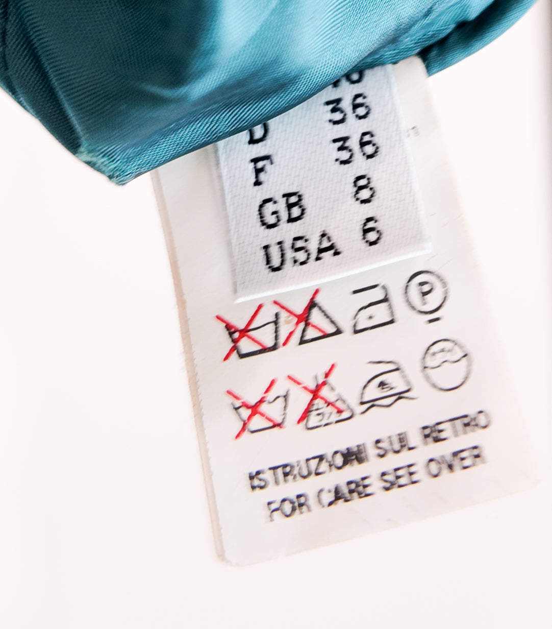 Close-up of a care label on a garment with text and symbols.
