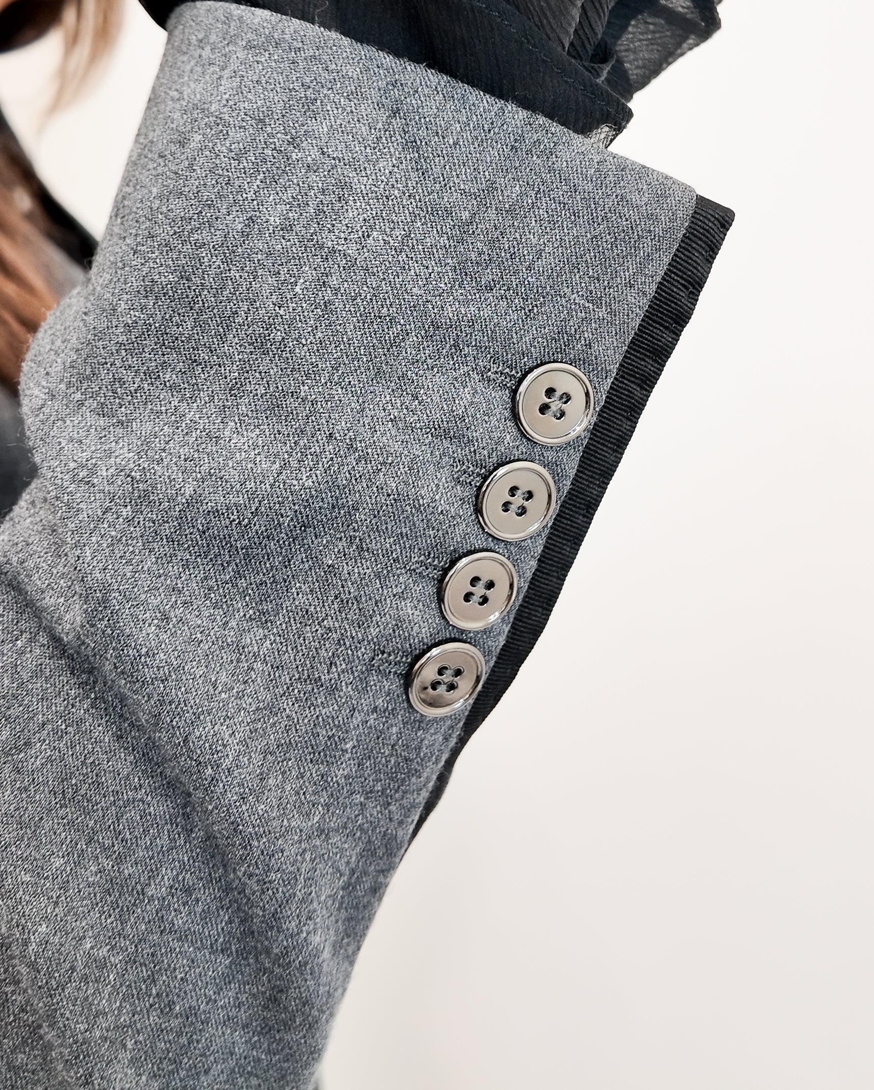 Close-up of a gray coat with button details on a light background