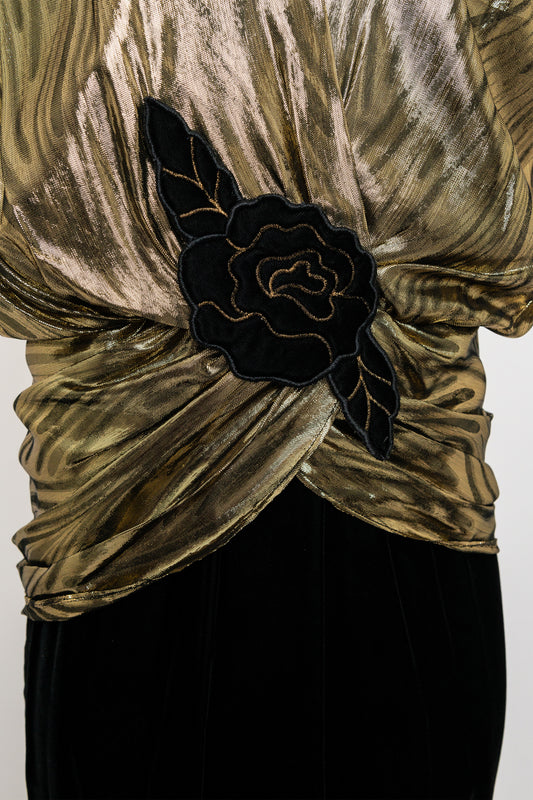 Gold velvet top with black floral accessory on a white background