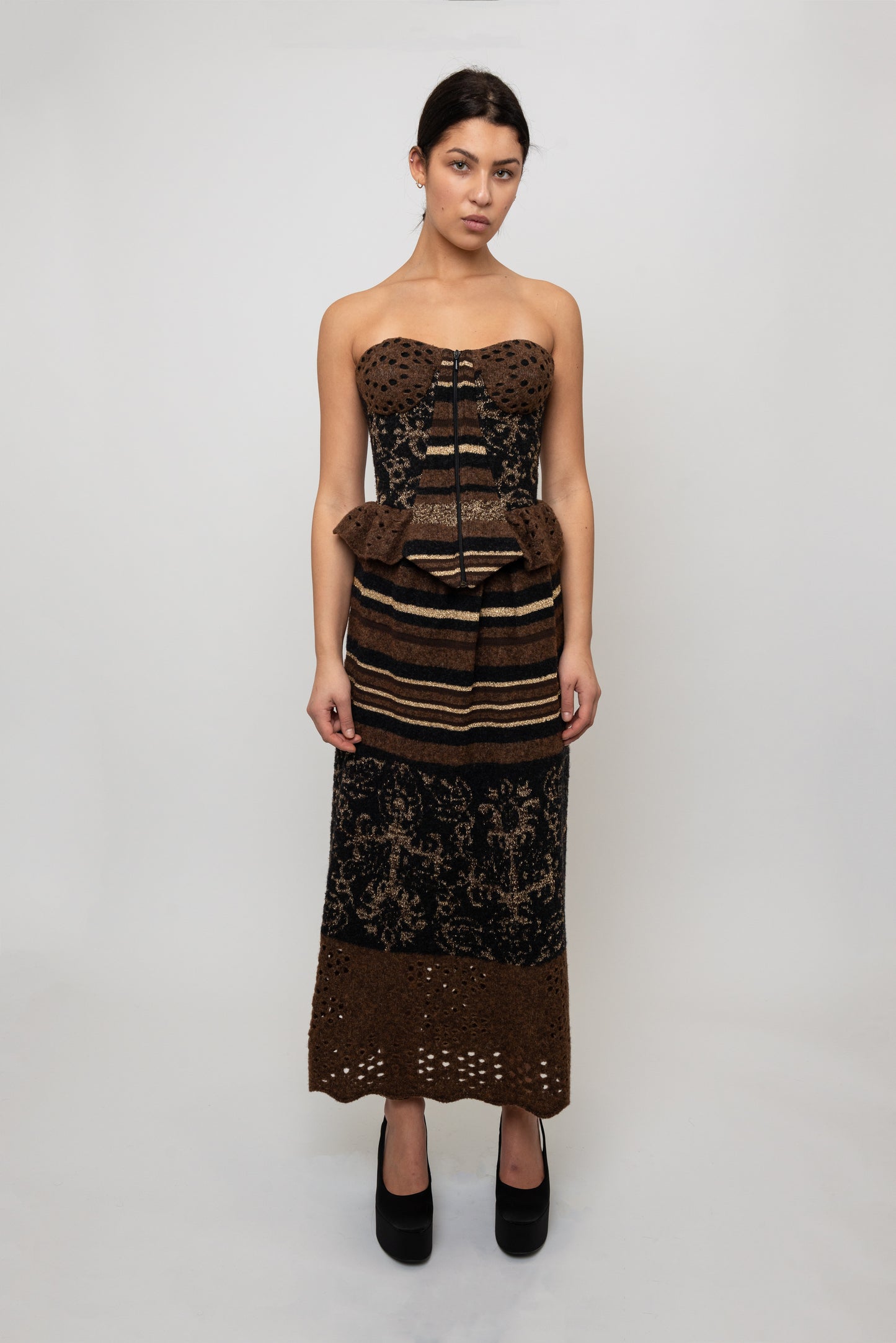 Model wearing a strapless, patterned top and with a  skirt on a white background