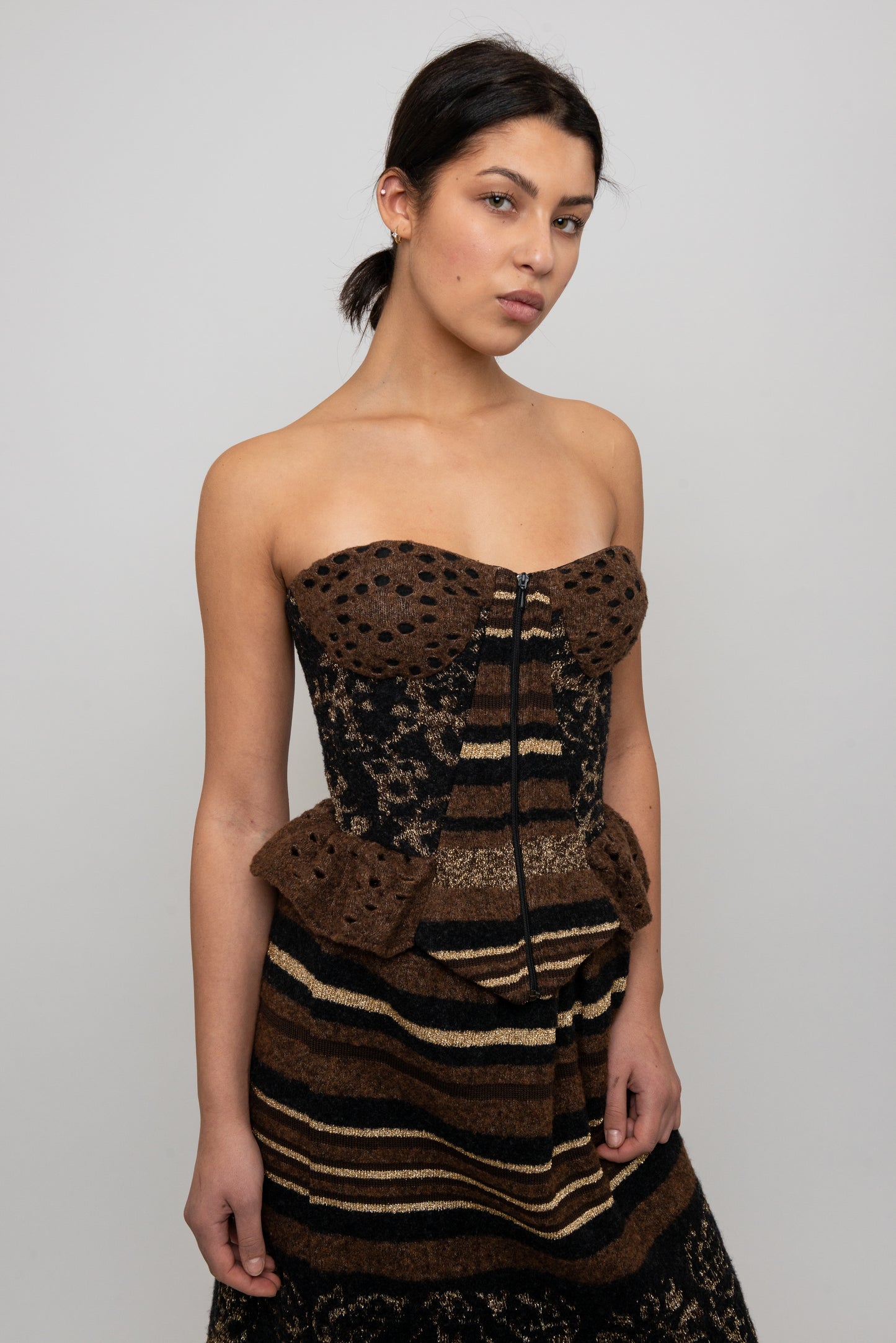 Woman wearing a strapless, knit patterned top and skirt against a plain background