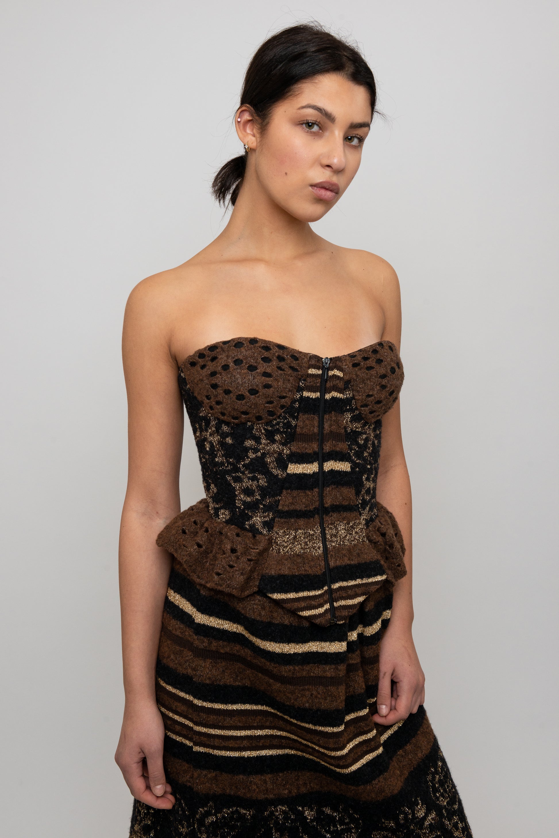 Woman wearing a strapless, knit patterned top and skirt against a plain background