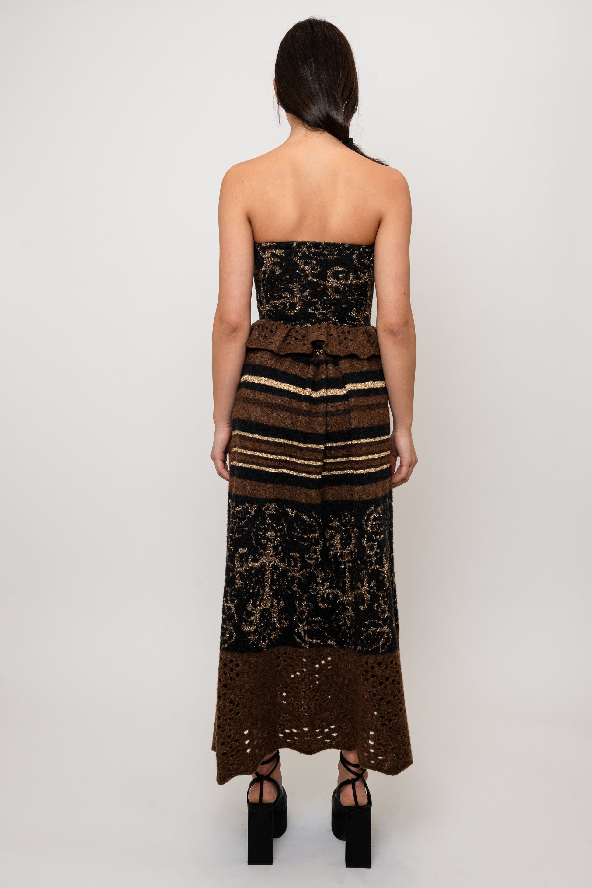 Woman wearing a strapless knit top and skirt with  brown stripes on a white background