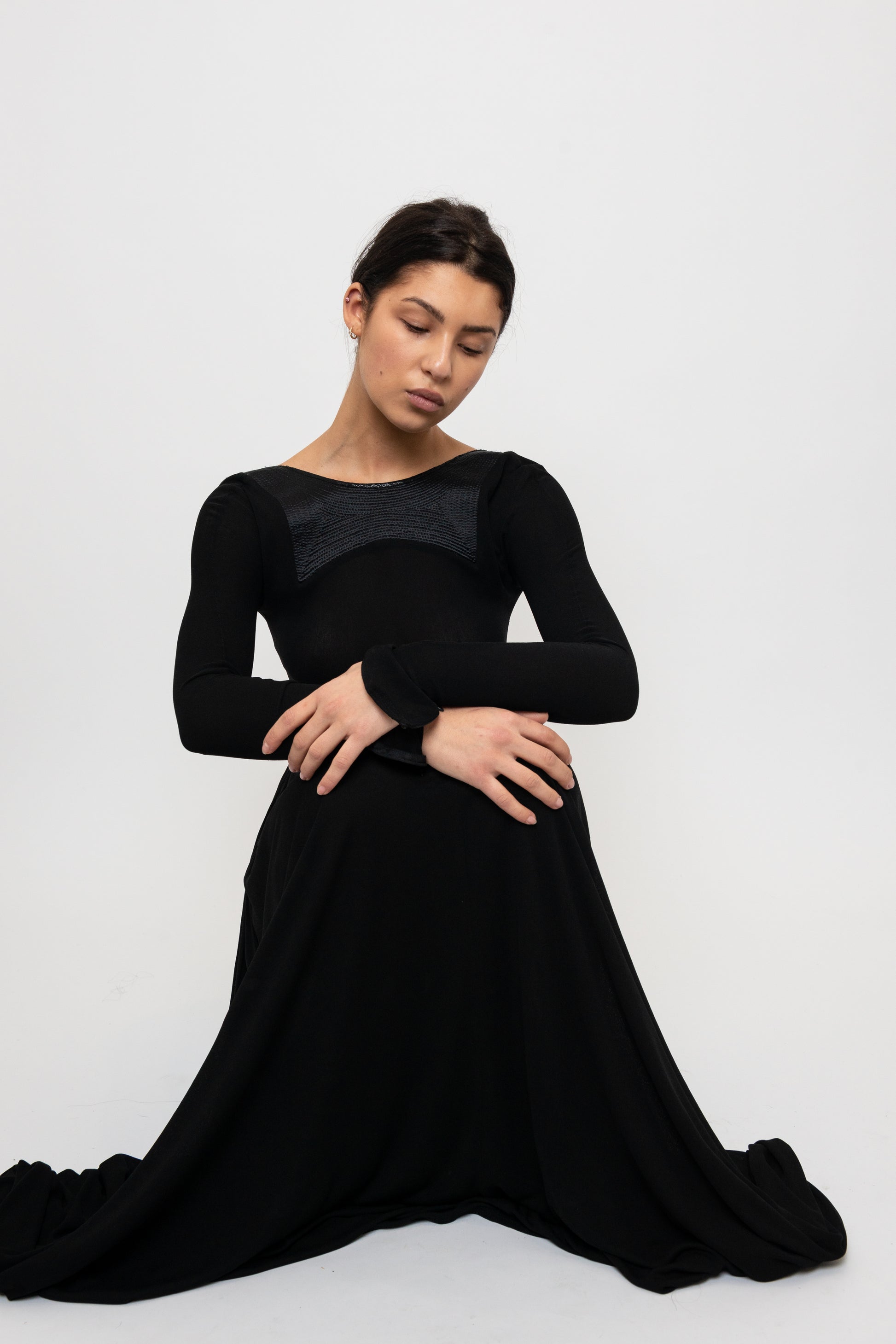 Woman sitting in a black long sleeve formal gown
