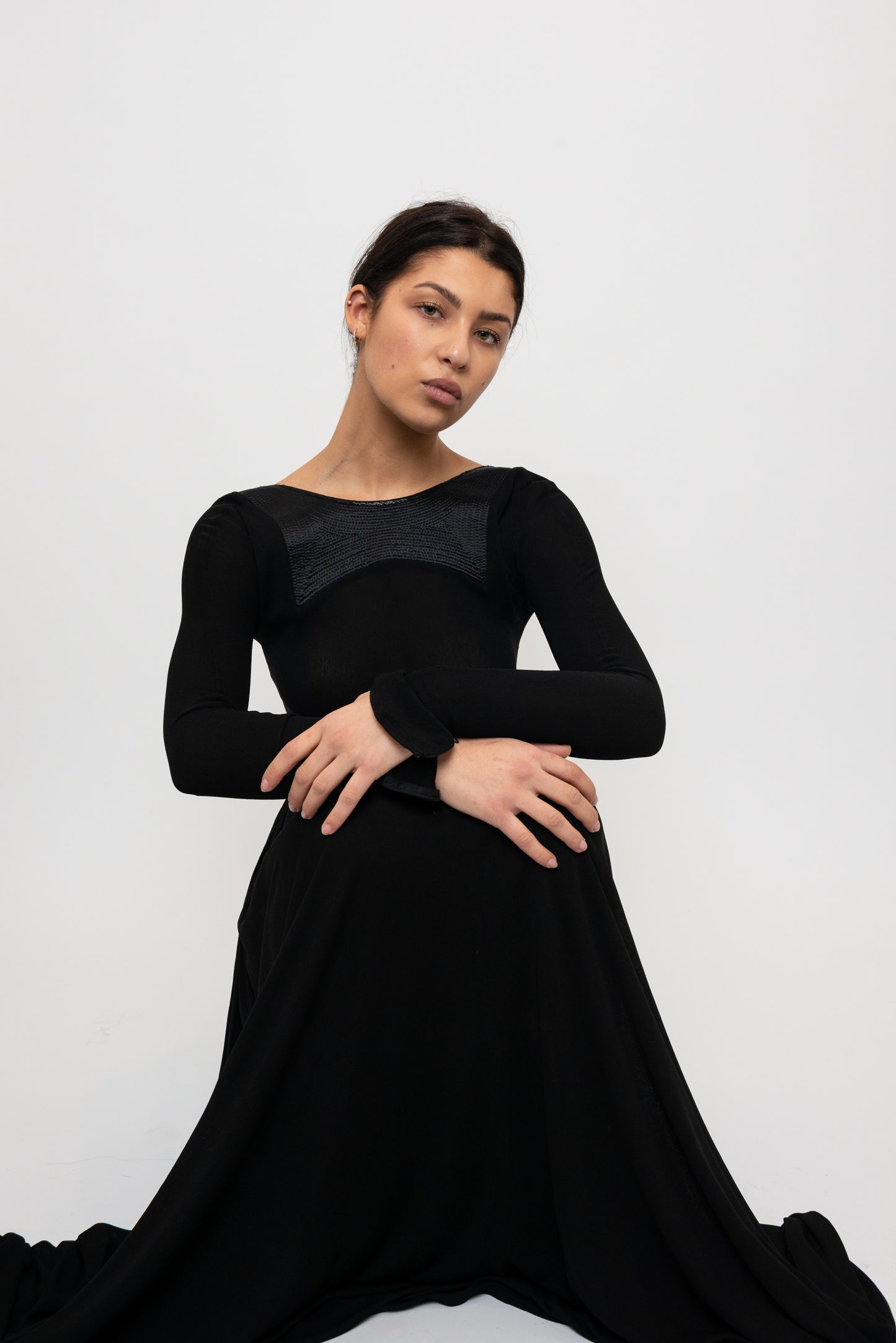 Woman sitting in a black long sleeve formal gown