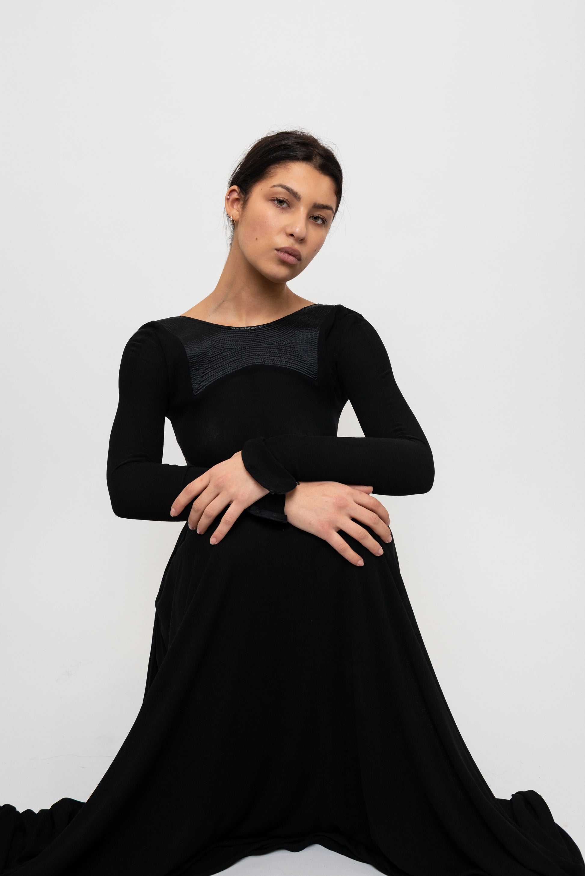 Woman sitting in a black long sleeve formal gown