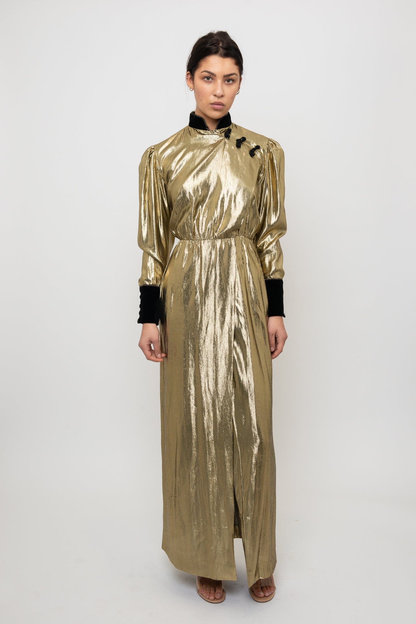 Woman wearing a gold metallic dress with black accents on a white background