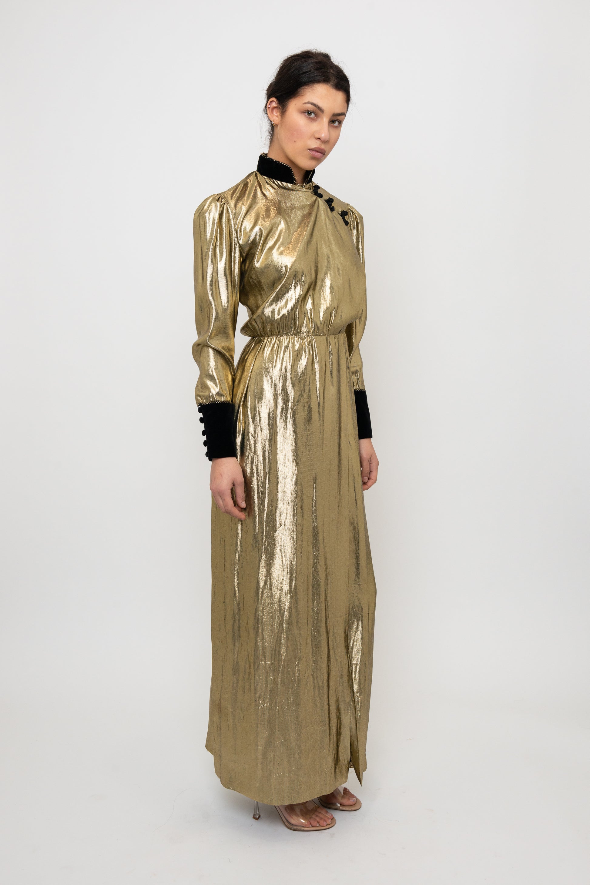 Woman wearing a gold metallic dress with black accents on a white background
