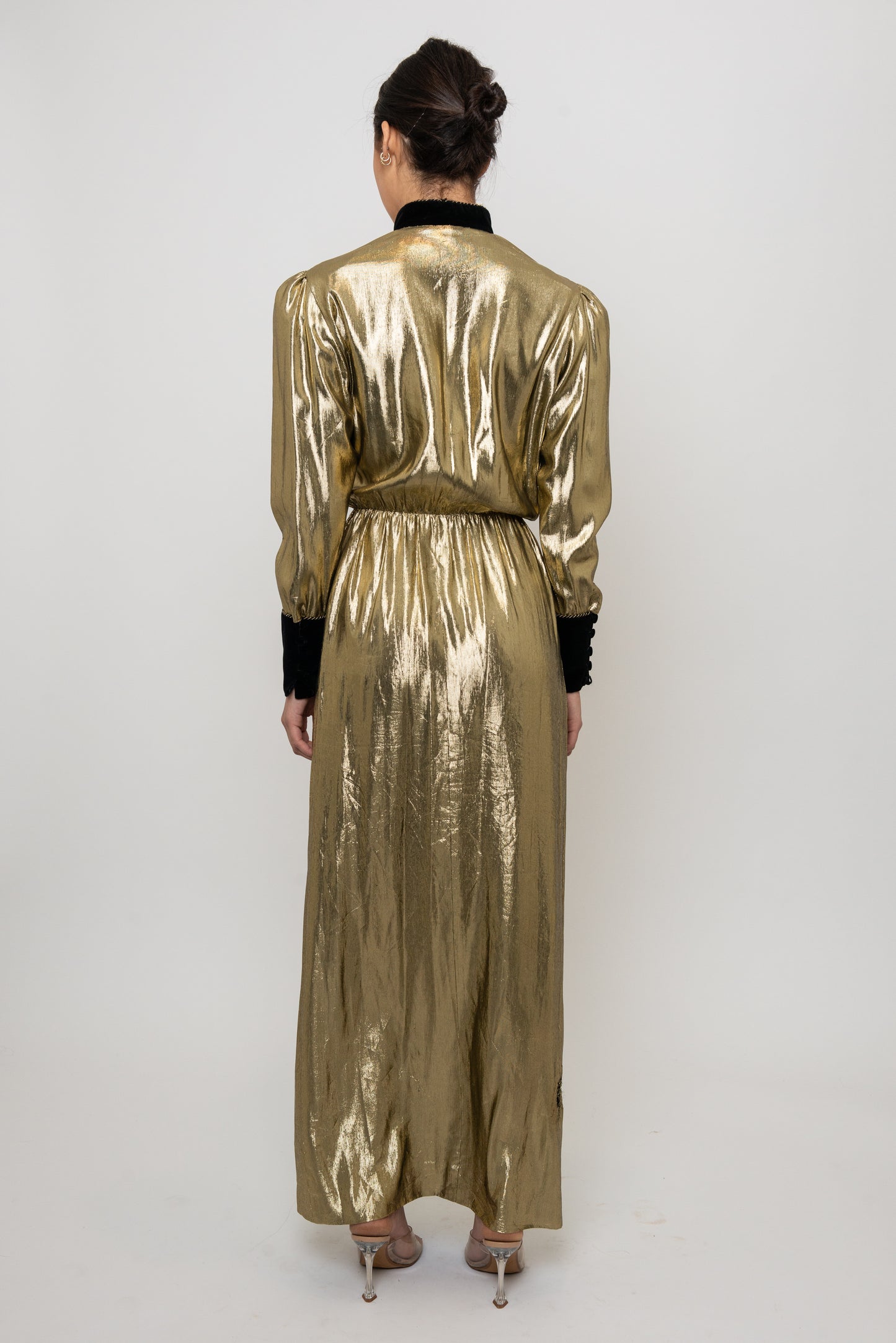 Person wearing a gold metallic jumpsuit on a white background
