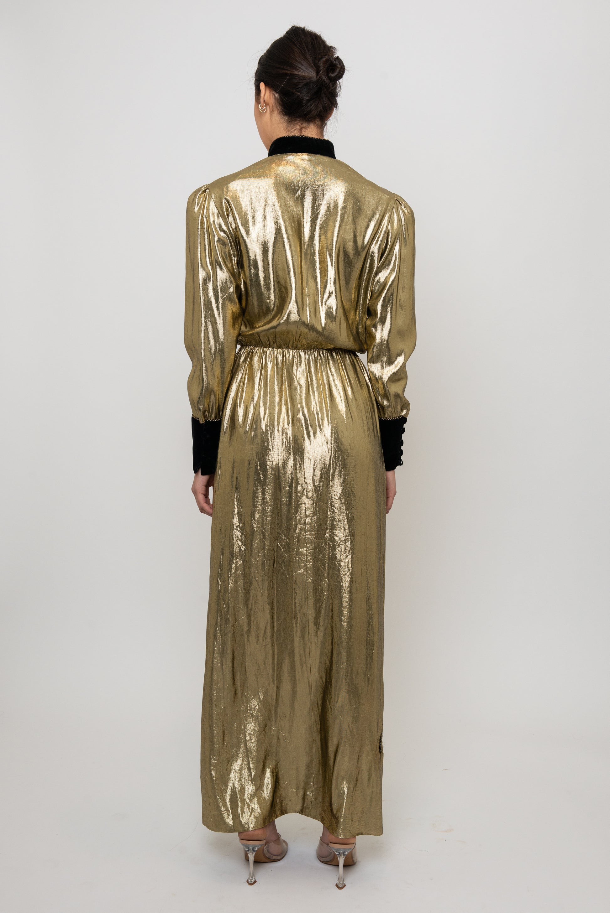 Person wearing a gold metallic jumpsuit on a white background