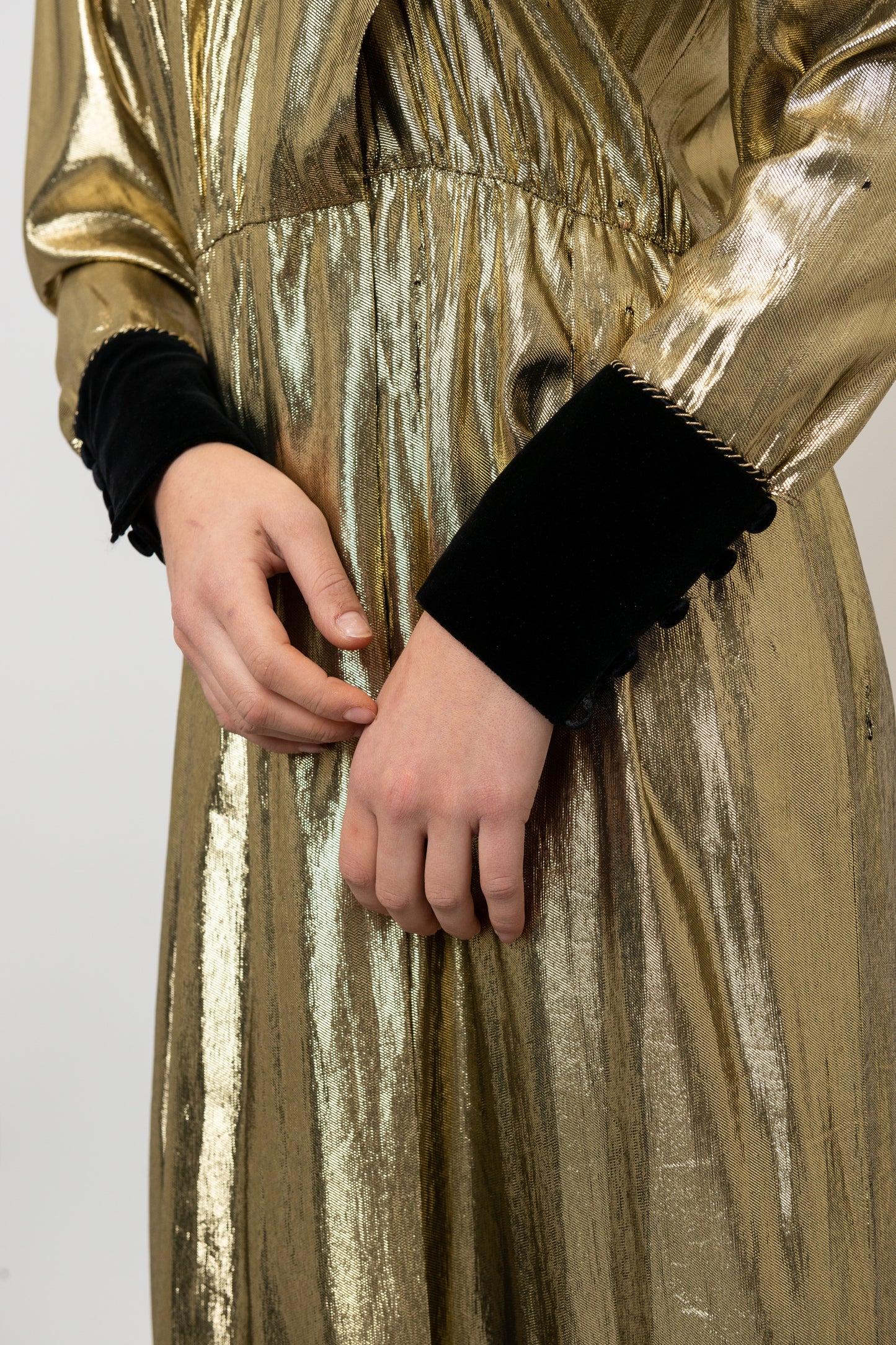 Gold metallic dress with black cuffs on a plain background