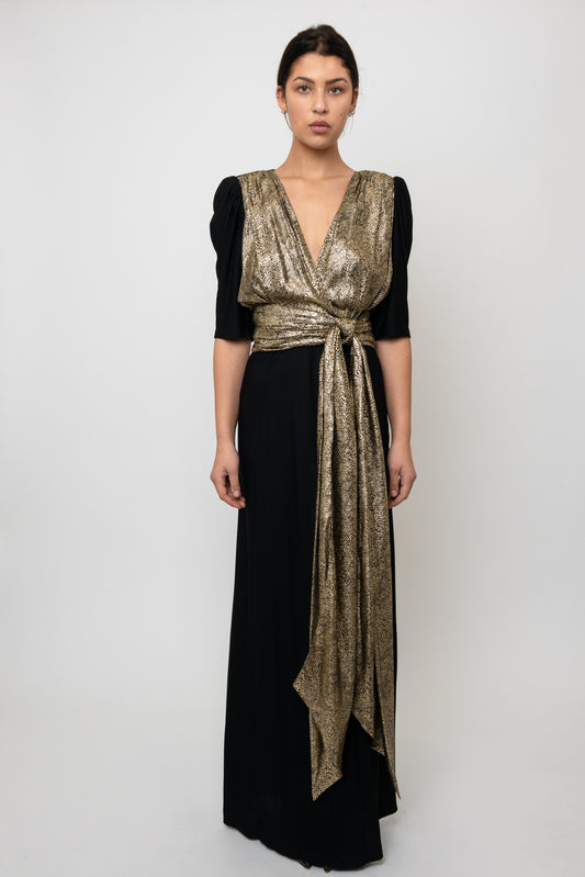 Woman wearing a black and gold dress with a plain background