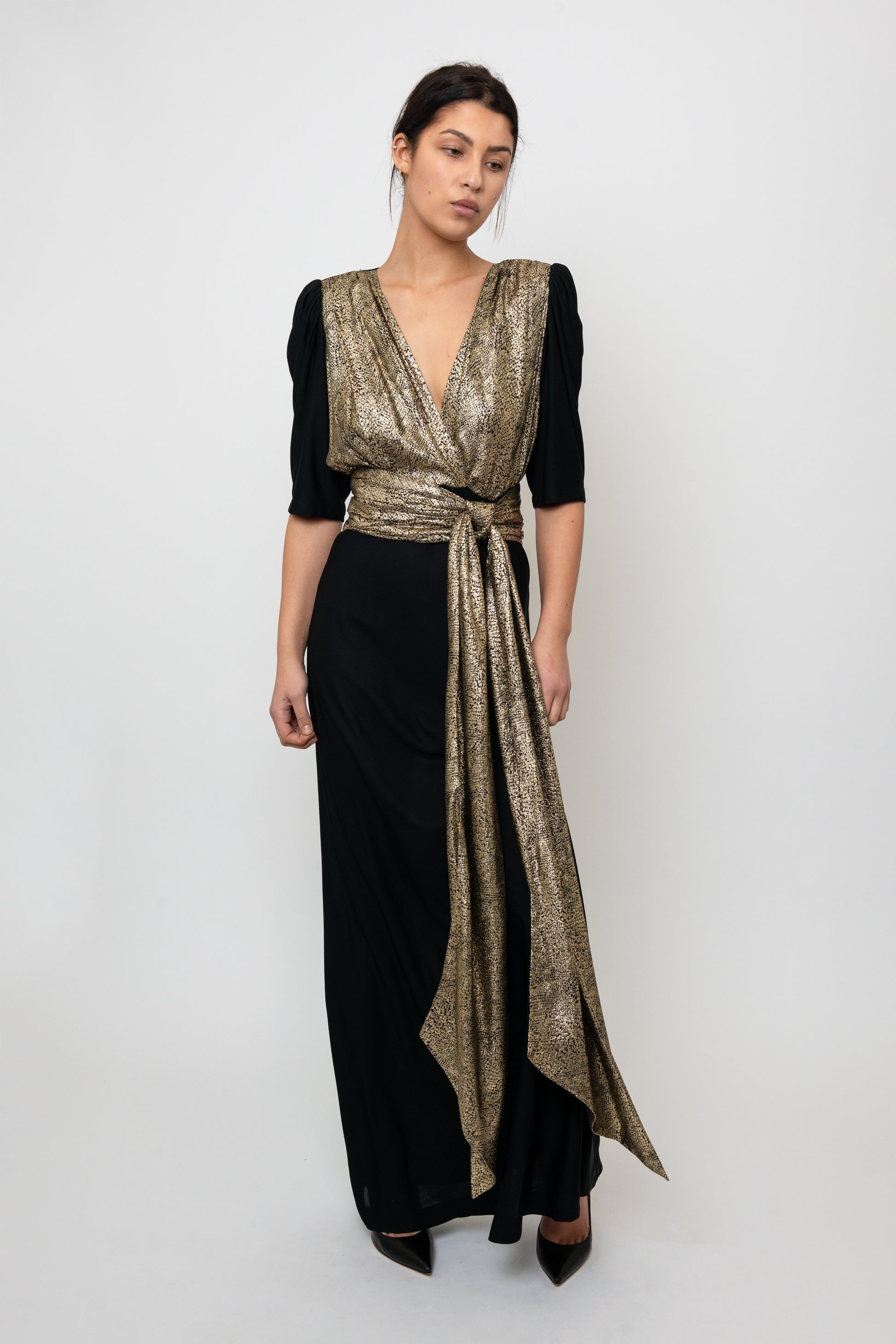Woman wearing a black and gold dress with a white background