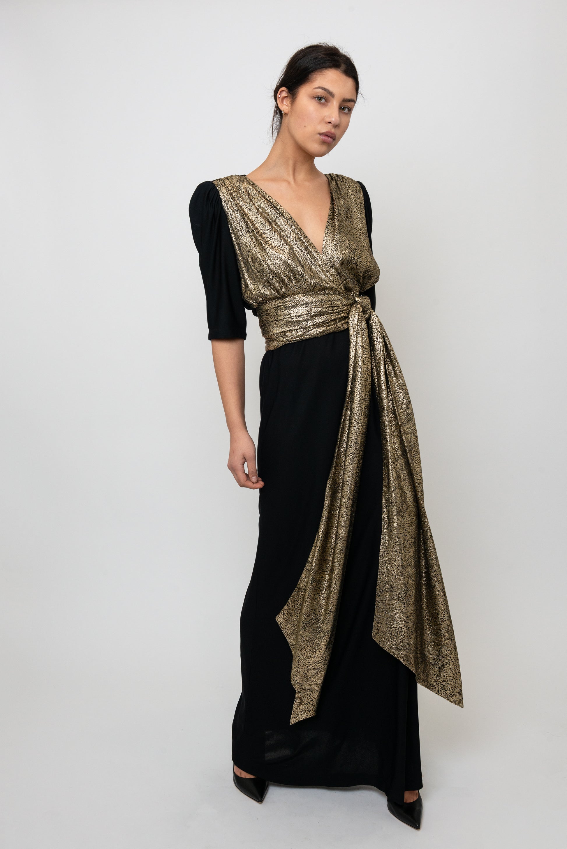 Woman wearing a black dress with a gold wrap over a white background