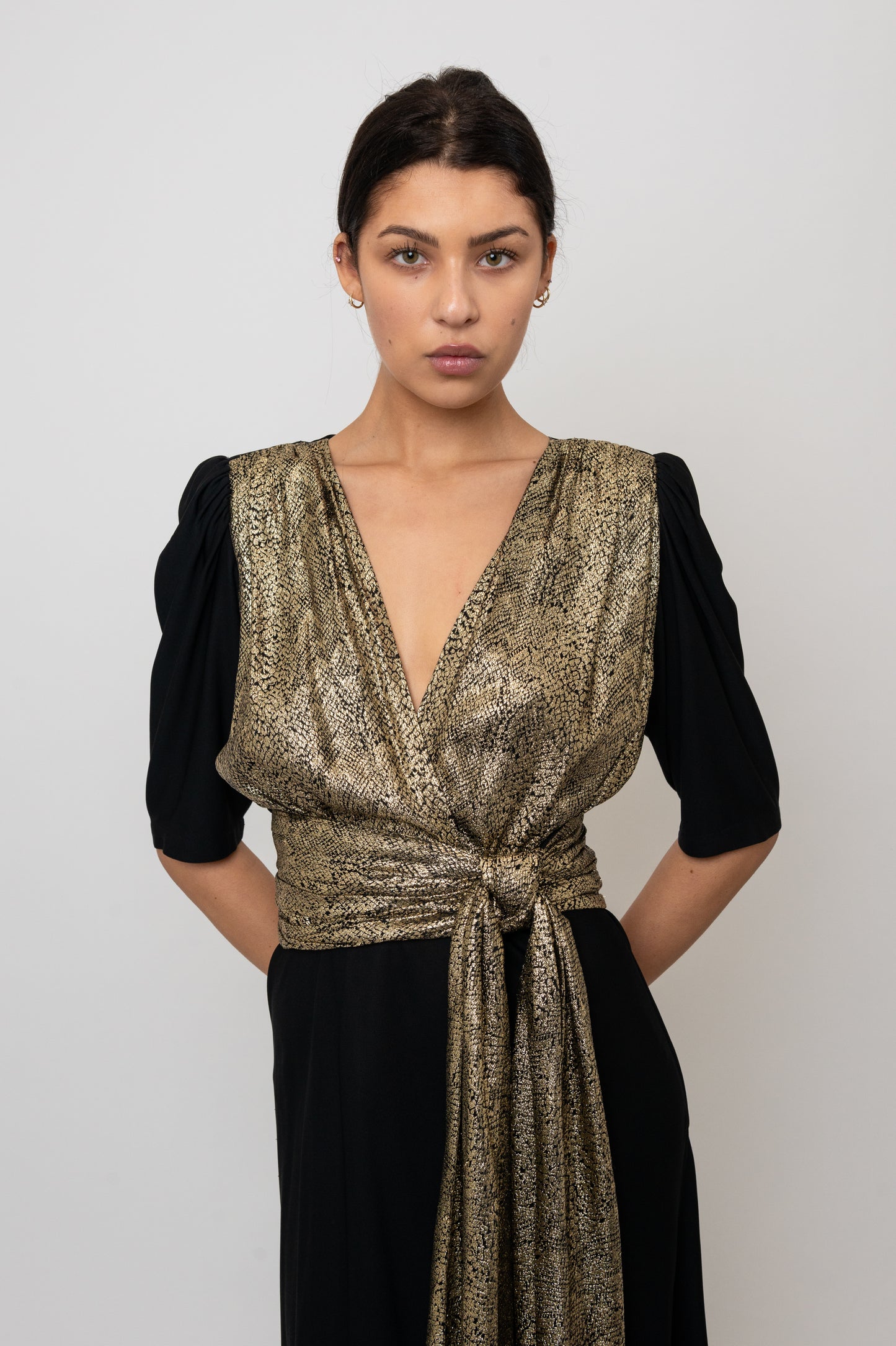 Woman wearing a gold and black dress against a white background