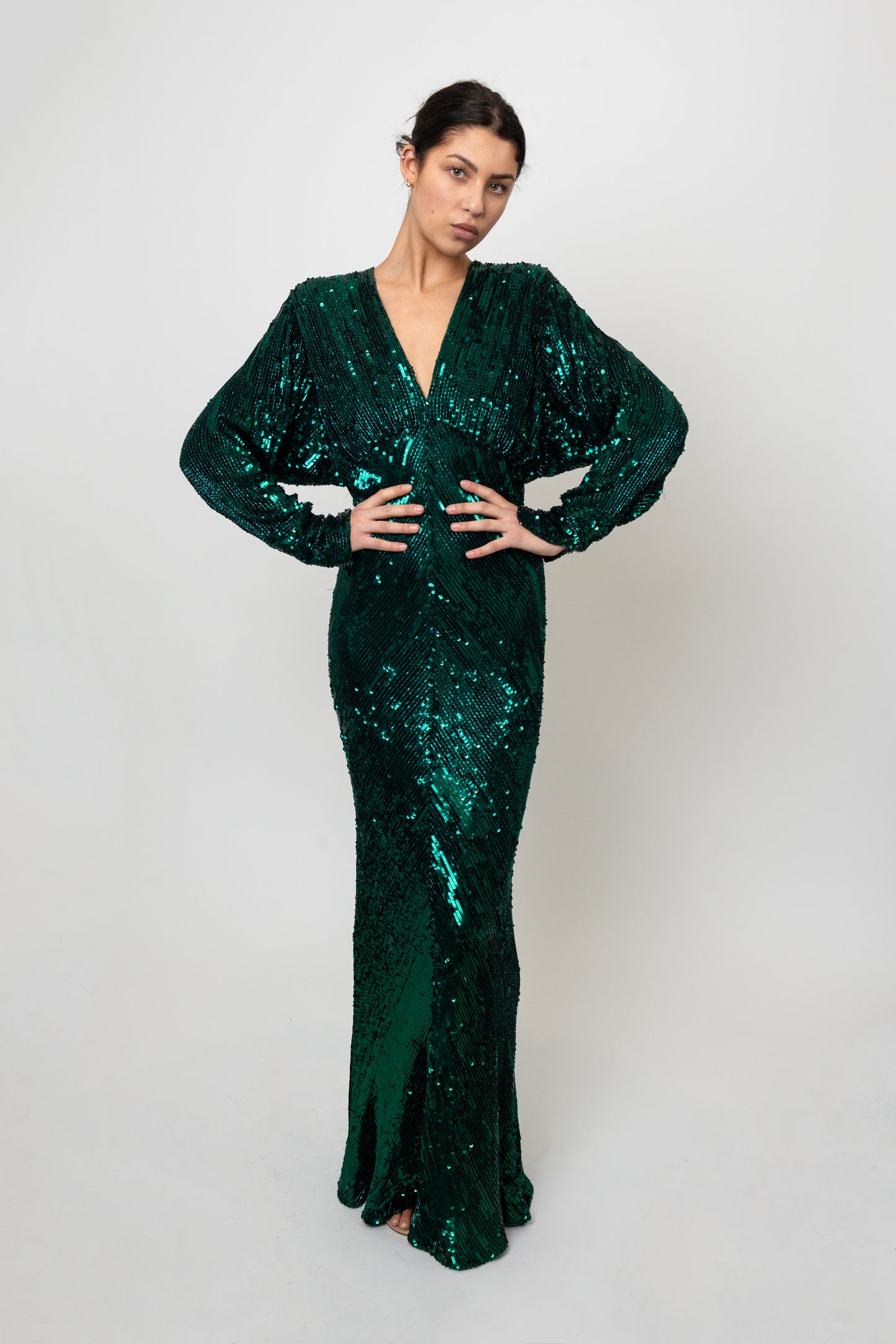 Woman wearing a green sequin dress against a white background