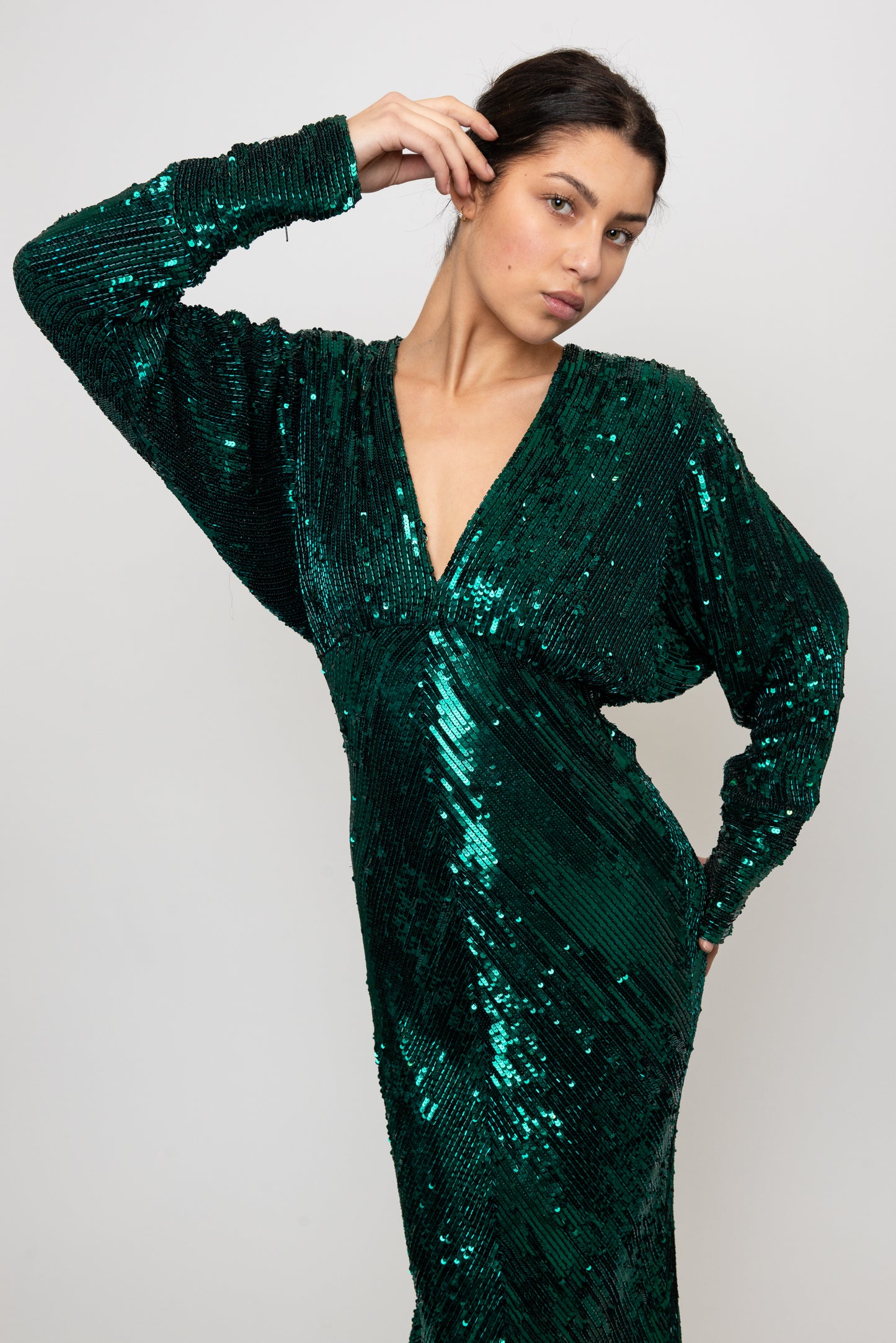 Woman wearing a green sequin dress against a white background