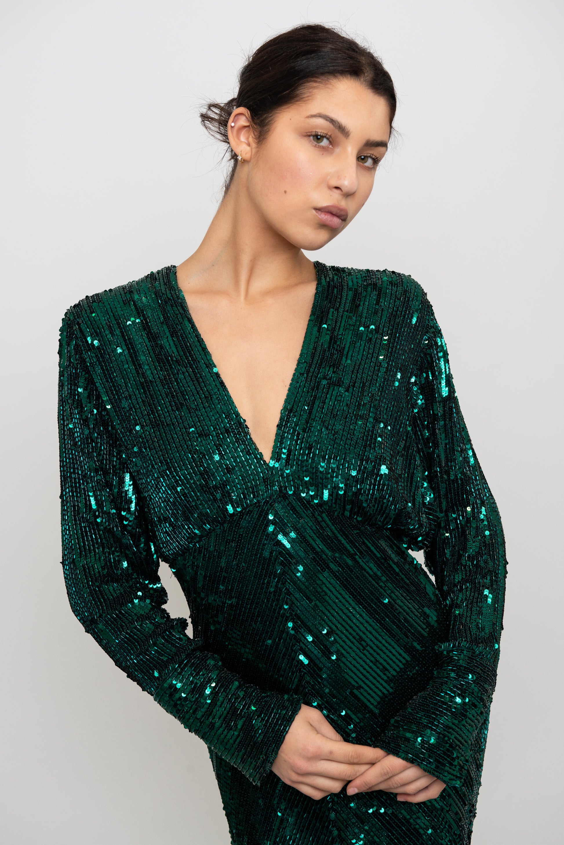 Woman wearing a green sequin dress against a white background