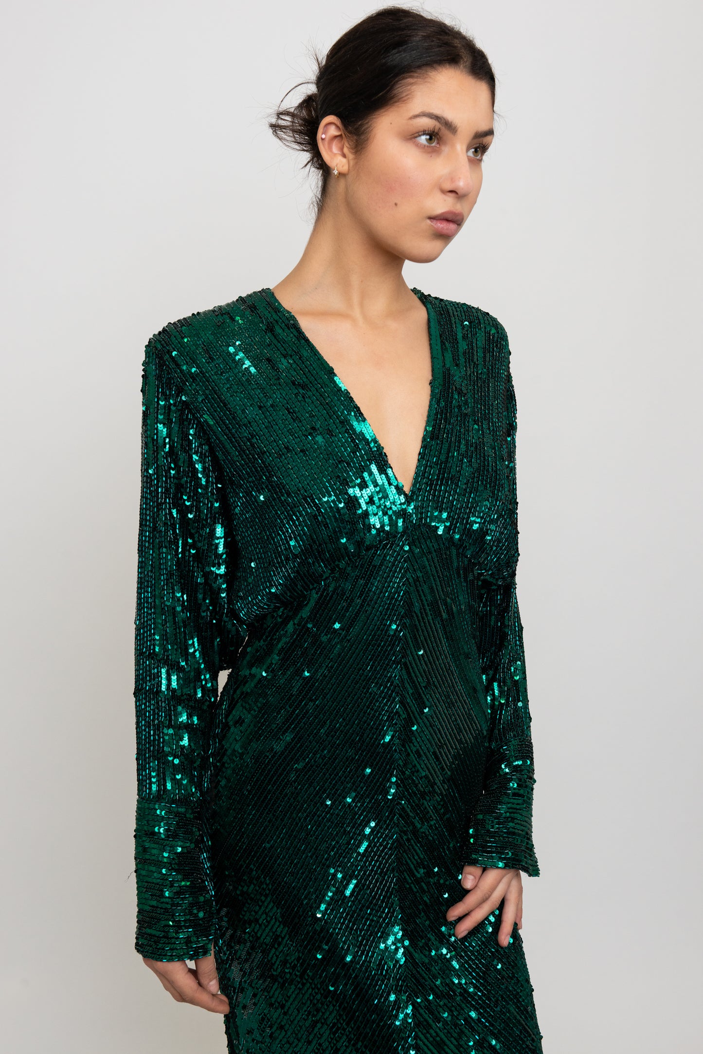 Woman wearing a green sequin dress against a white background