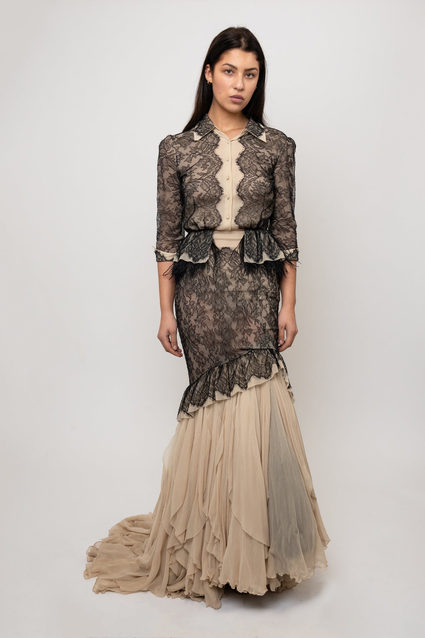 Woman wearing a lace dress with a fitted bodice and flowing skirt on a white background