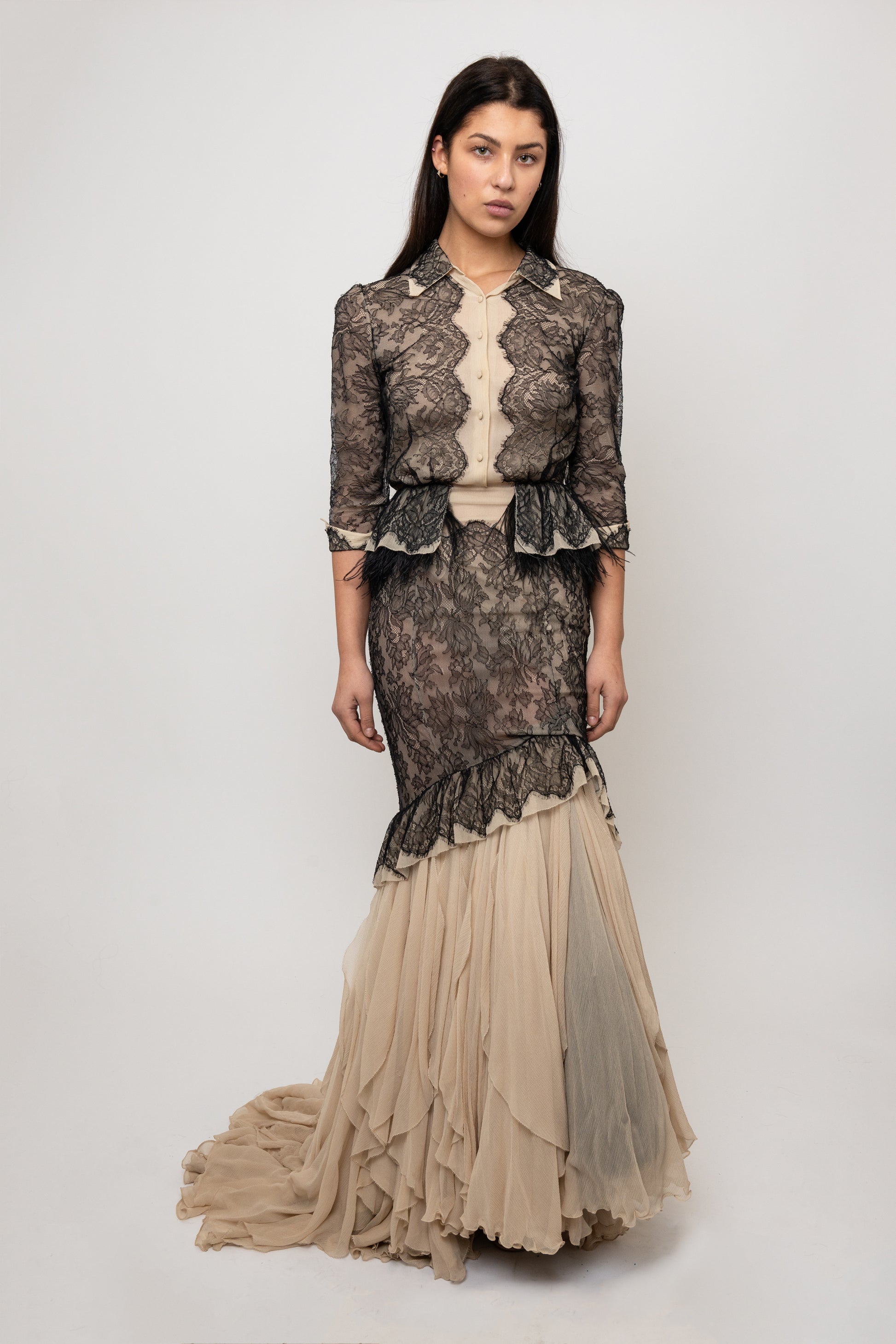 Woman wearing a lace dress with a fitted bodice and flowing skirt on a white background