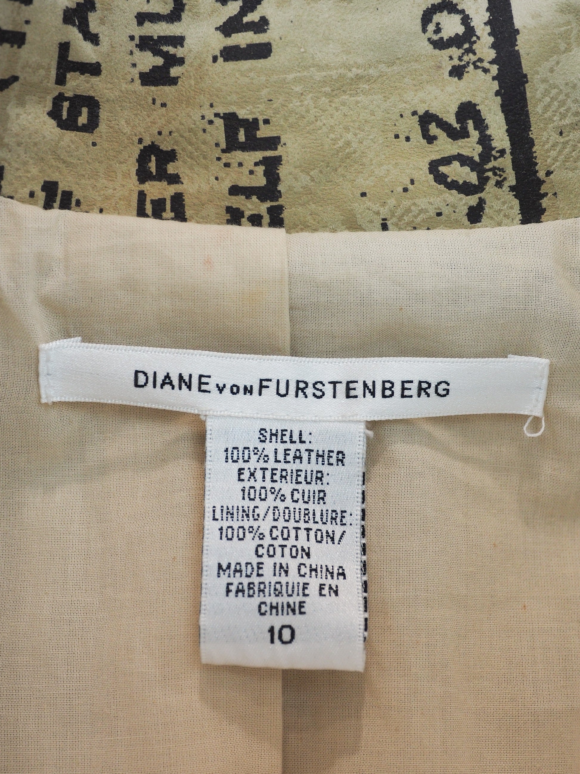A Diane Von Furstenberg beige trench coat with an all-over black vintage map and script print, featuring a double-breasted design with brown buttons and a matching waist tie, shown against a plain white background.