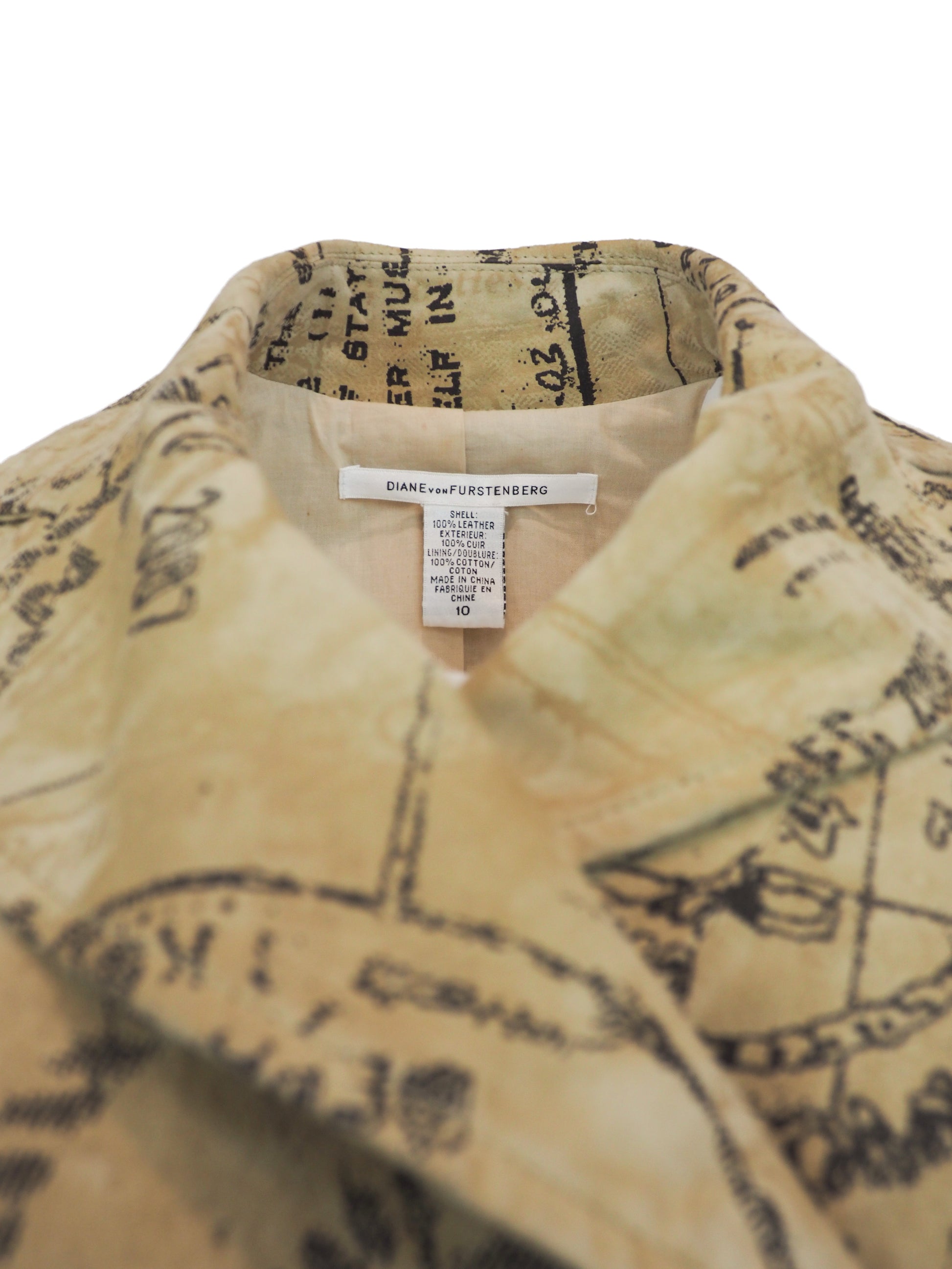 A beige trench coat with an all-over black vintage map and script print, featuring a double-breasted design with brown buttons and a matching waist tie, shown against a plain white background.