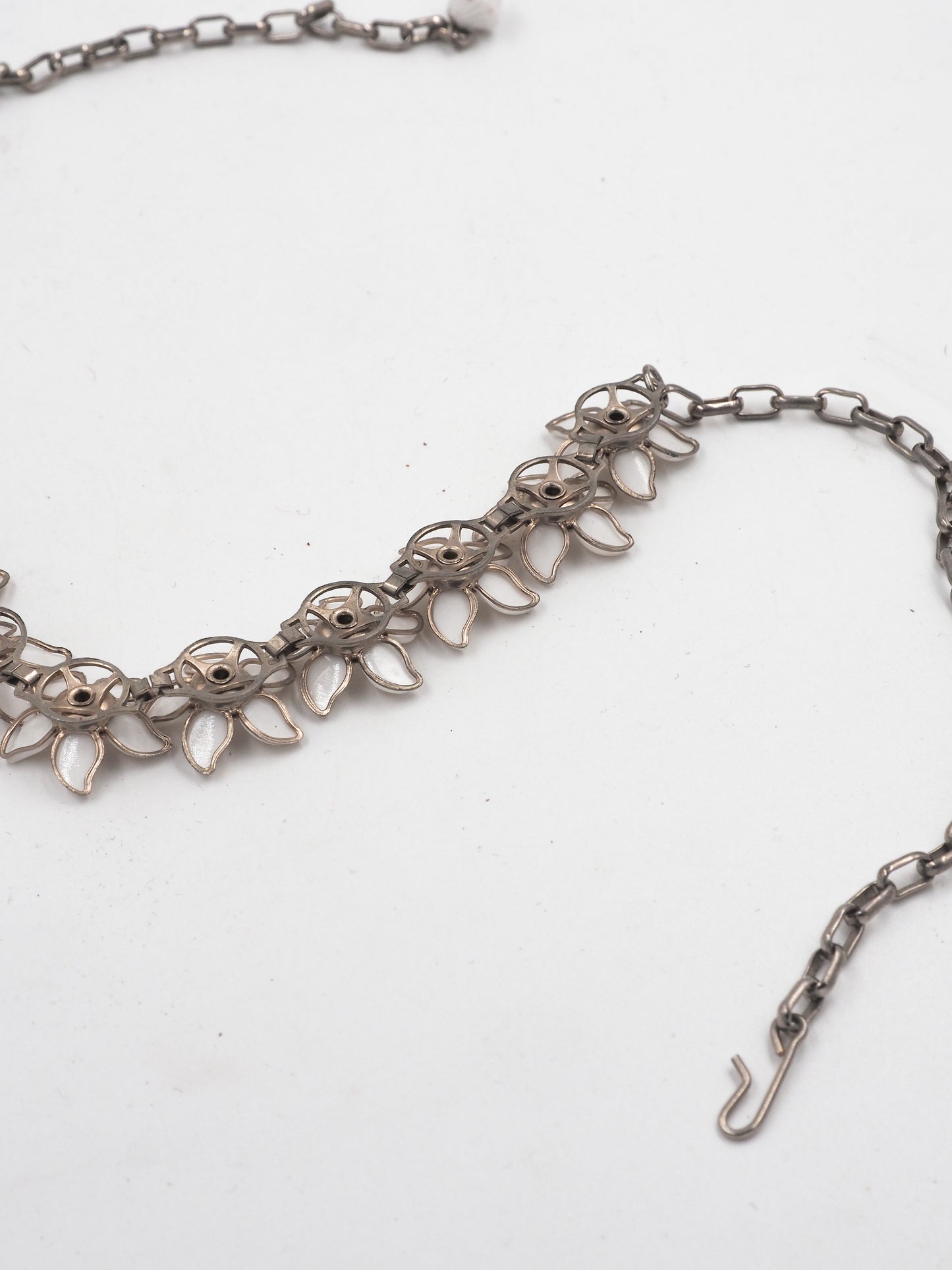 A vintage bridal silver-tone chain necklace featuring a row of white enamel flower blossoms with small clear rhinestone accents