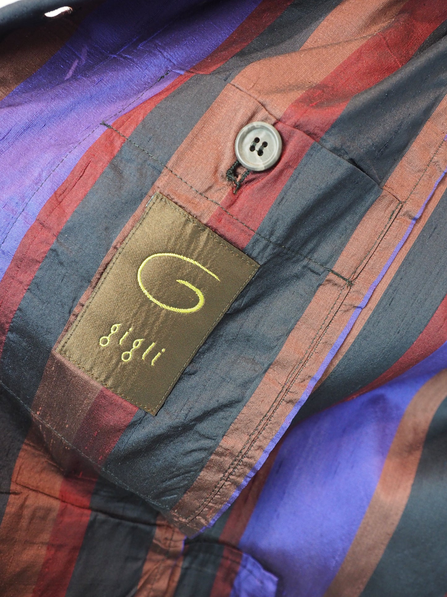 Romeo Gigli Vintage. A long-sleeve striped blazer with vertical stripes in purple, rust red, and black, featuring a three-button front closure and flap pockets.