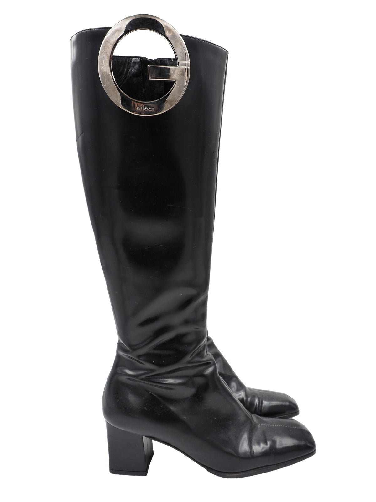 A vintage gucci 1990s black leather knee-high boot with a chunky block heel and a large circular silver-tone metal ring logo detail near the top shaft