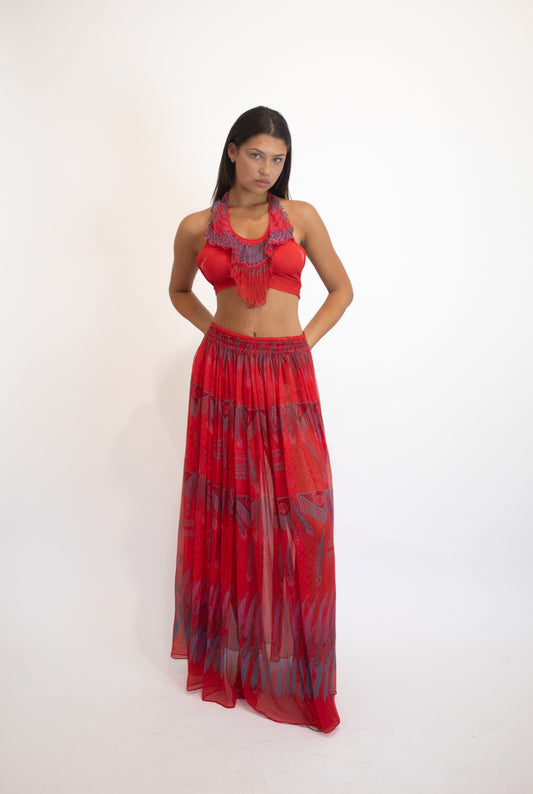 Woman wearing a red outfit with a patterned skirt on a white background