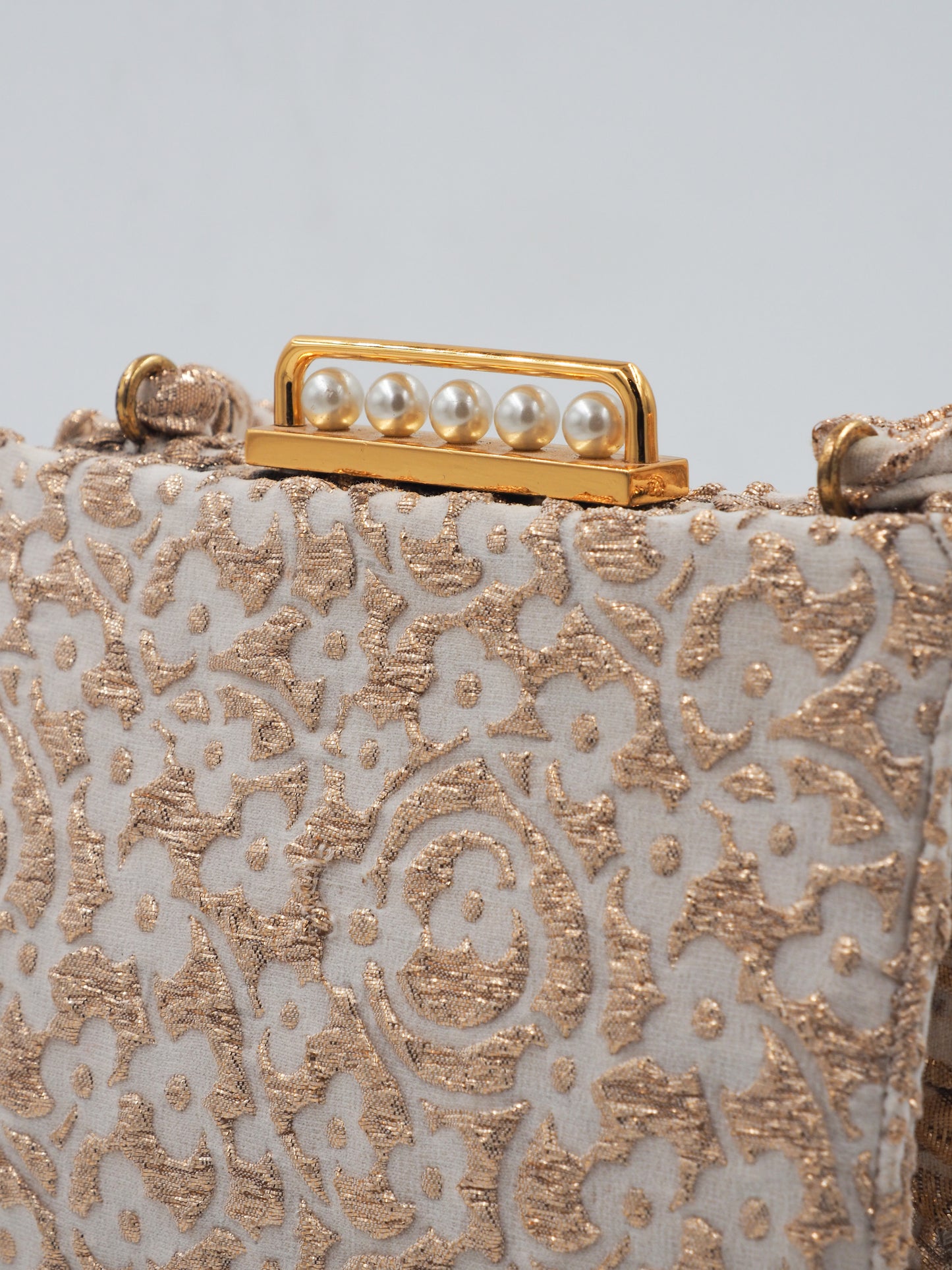 A 1960s Koret vintage structured evening clutch bag in beige and gold lace, featuring a braided top handle and a gold-tone metal clasp adorned with faux pearls
